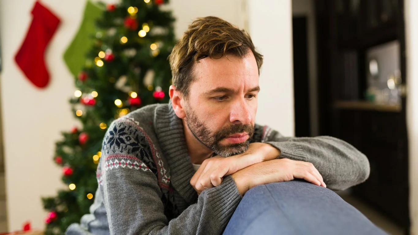Recognizing the winter blues - A man at home feeling sad during the holiday season.