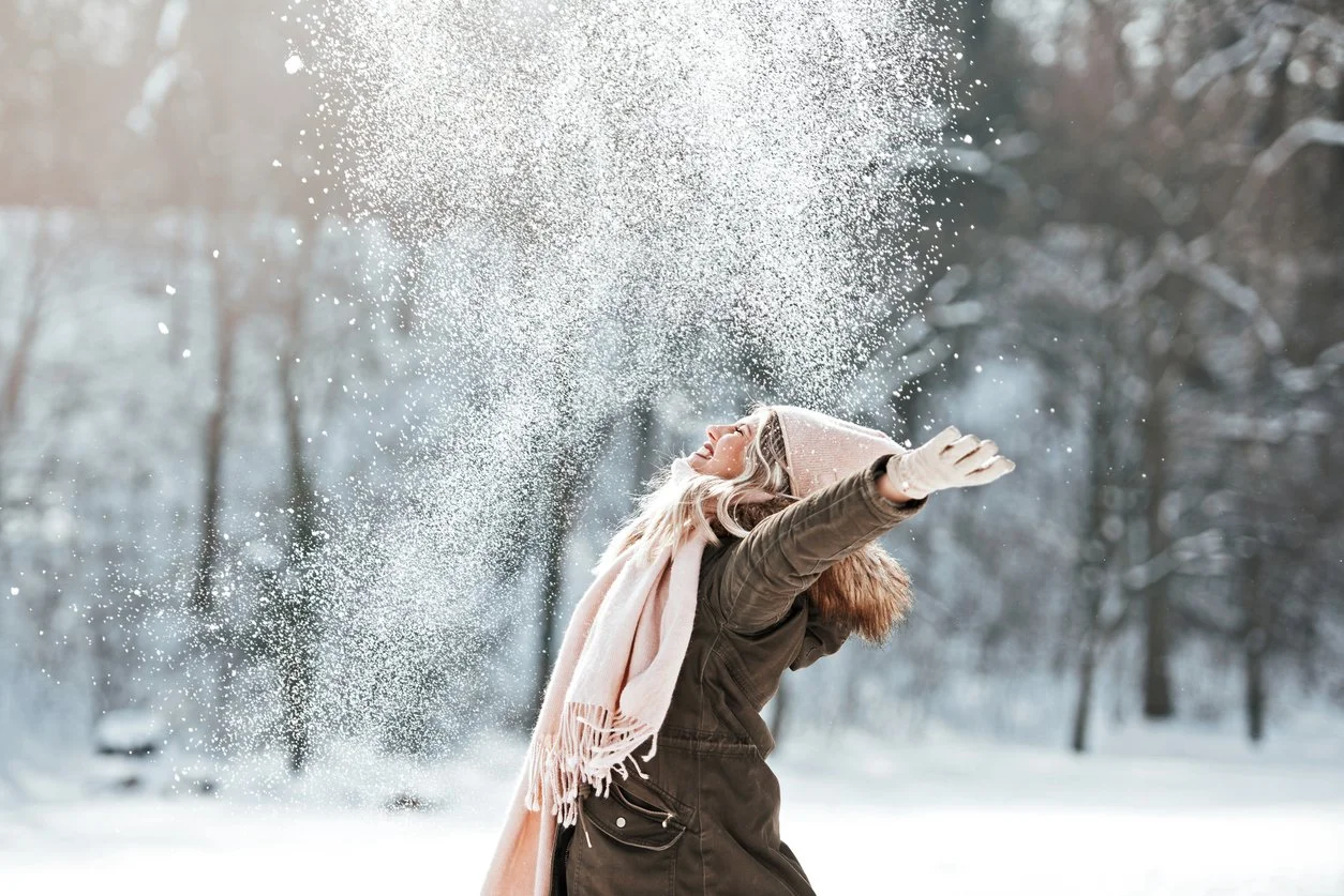 Beating the winter blues - A woman outdoors playing in the snow.