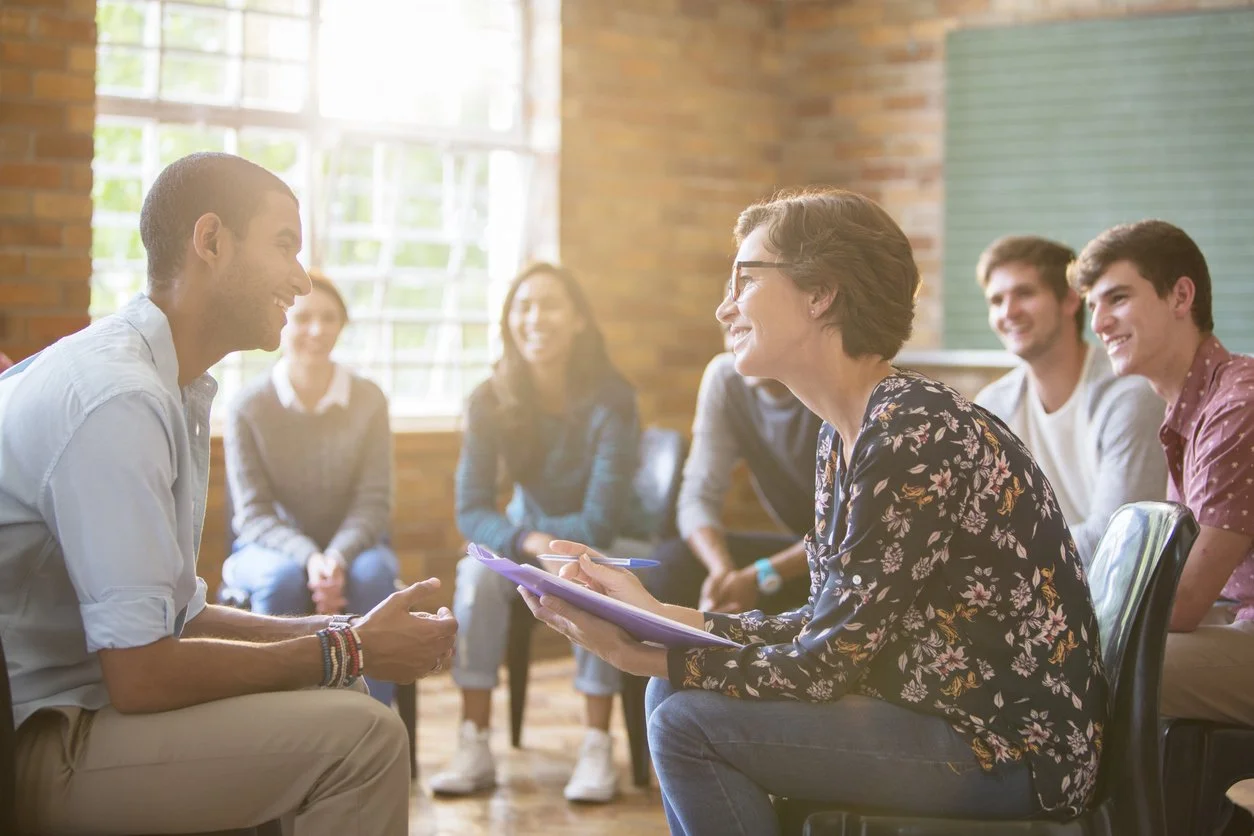 Navigating immigration and assimilation - A woman speaking with a male immigrant during a support group session.