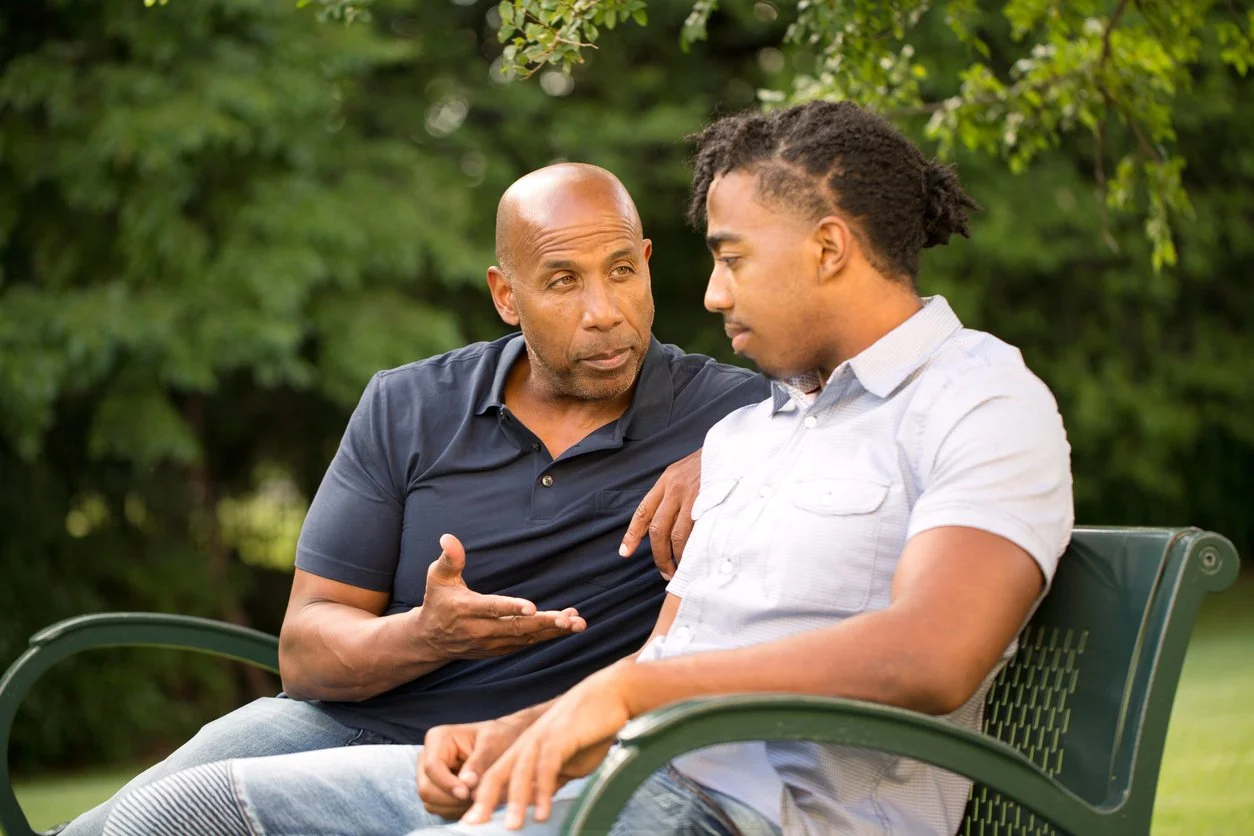 Discussing proper firearm storage - A father and son having a private talk outdoors.