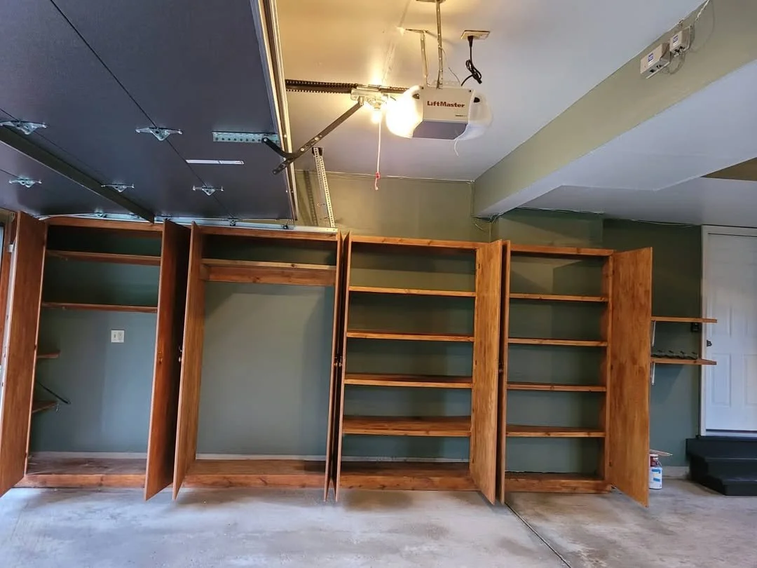 Painted garage walls and ceiling with wooden shelves and cabinets.