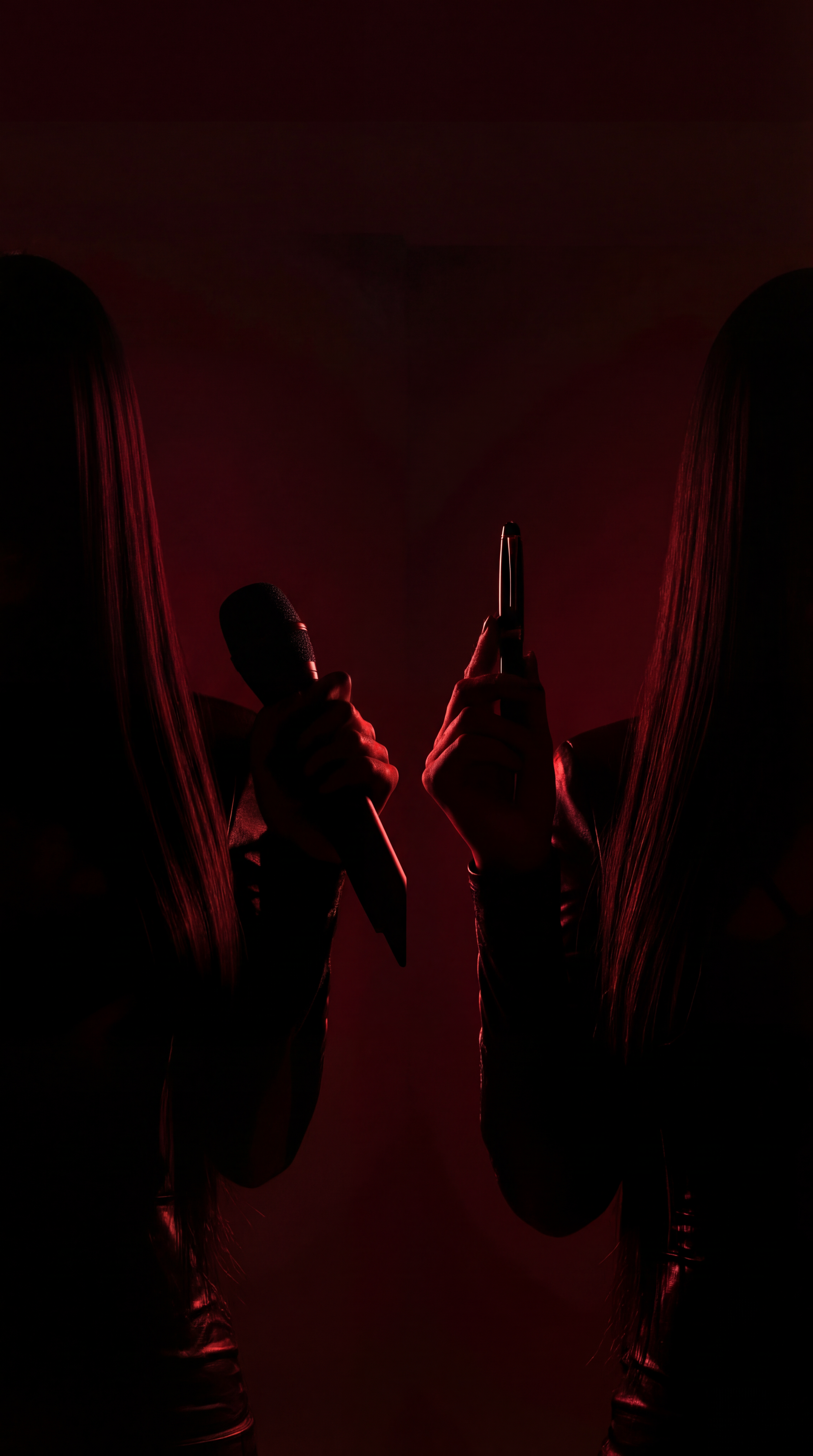 Silhouetted person holding microphone and a vape pen in a dark, red-lit environment.