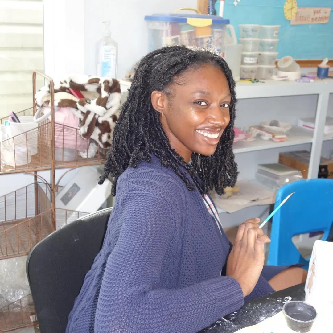 Teylor Parks owner of the Breathe in Color Art and Wellness Studio holding a paint brush and posing for a photo.