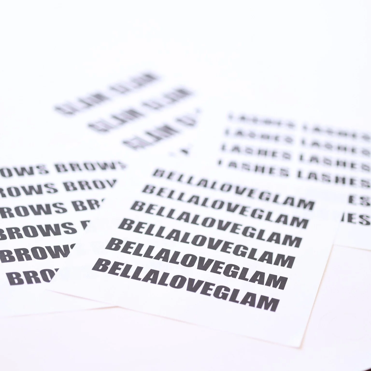 Multiple sheets of white paper with the repeated word 'BELLLOVEGLAM' printed in bold black font.