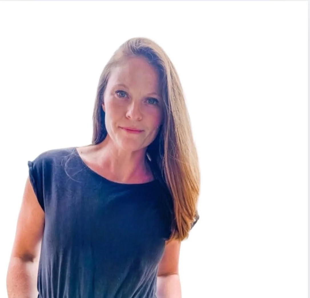 Canadian Financial Strategist Rebecca, a woman with long brown hair and blue eyes wearing a black sleeveless top standing against a plain white background to help Canadians get out of debt and build wealth