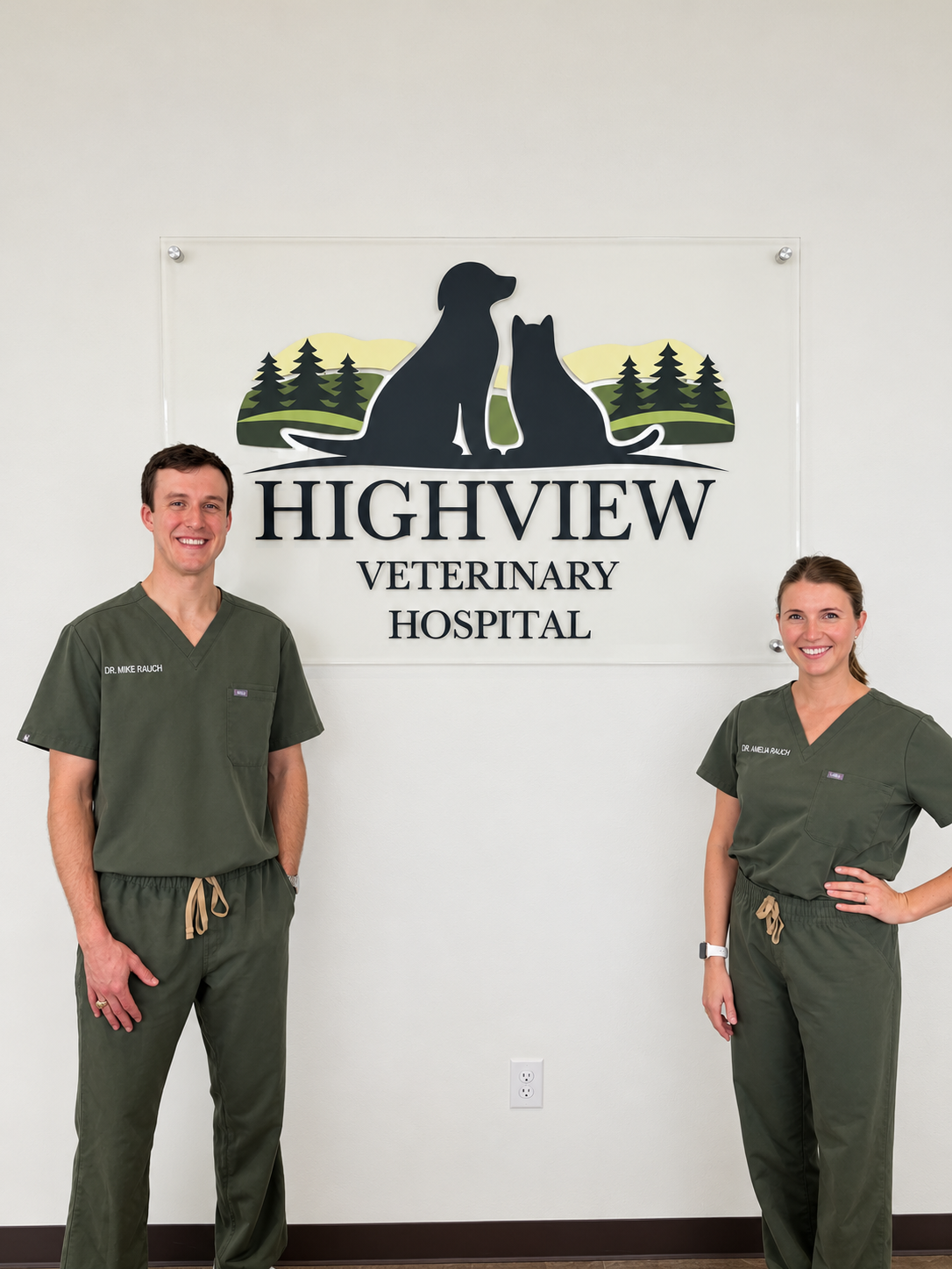 Dr. Mike Rauch and Dr. Amelia Rauch of Highview Veterinary Hospital standing in front of the Highview Logo in the lobby of their privately-owned veterinary practice in Boerne, TX.
