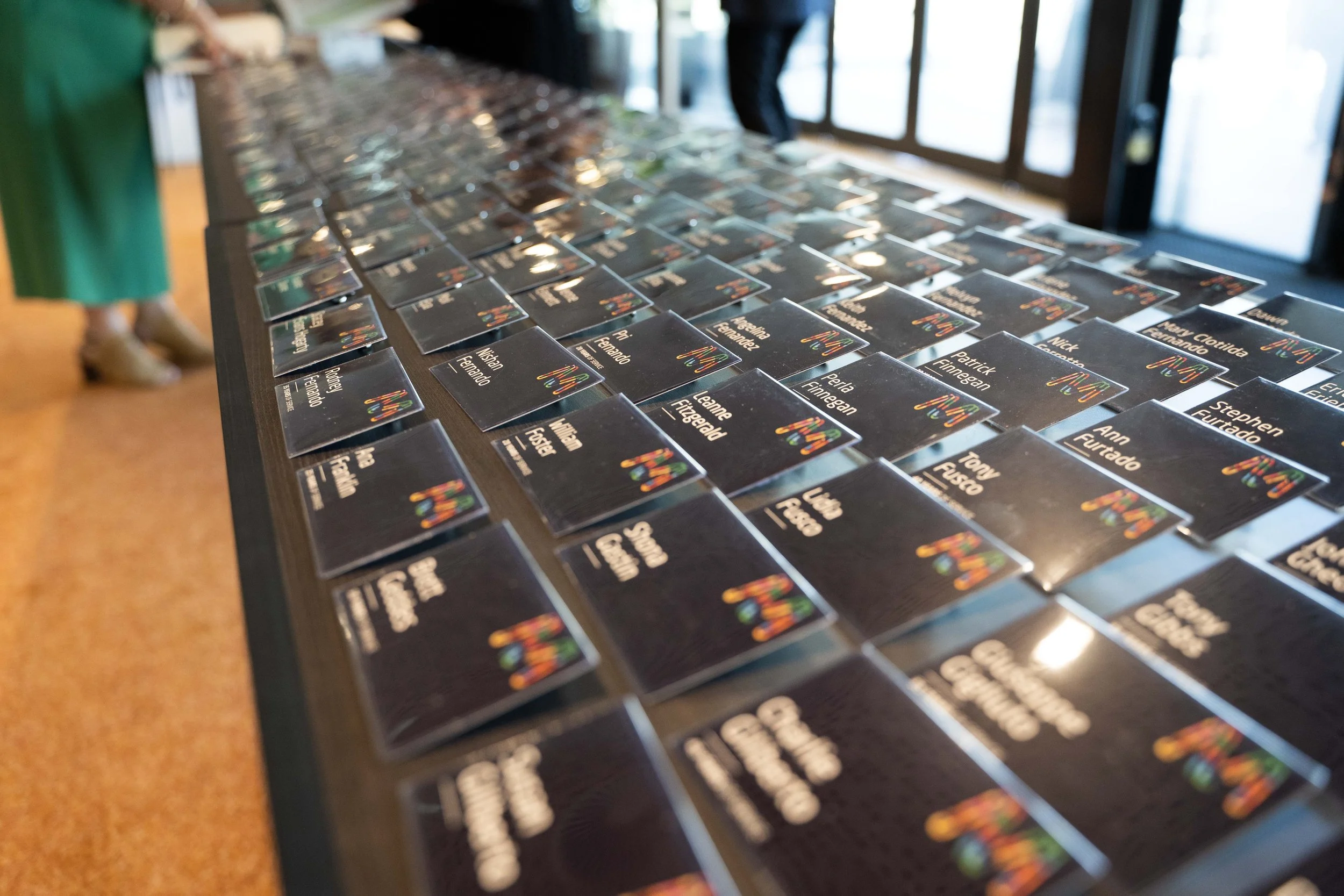 A table covered with name tags for an event, with a person standing near the table in the background.