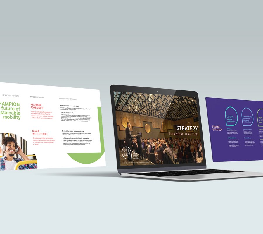Open laptop displaying a presentation titled "Strategy Financial Year 2023" with an audience in a decorated venue. To the left, digital presentation boards with graphs and text, including green, white, purple backgrounds, and a person smiling in a co