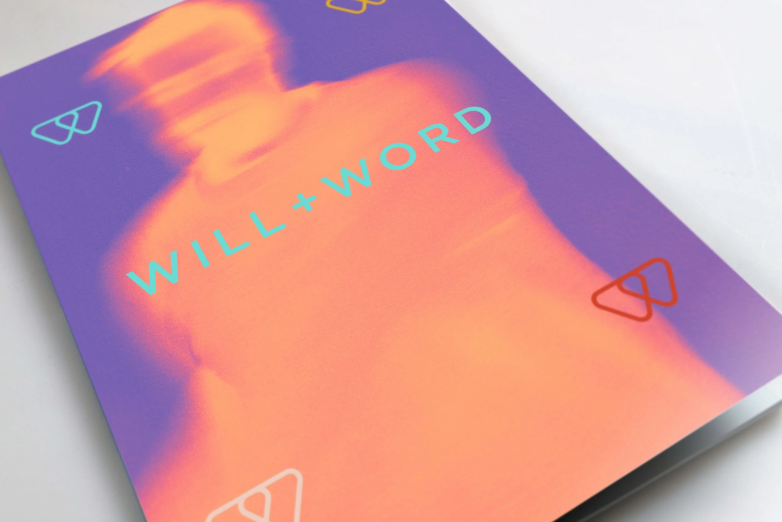 Close-up of a card with vibrant purple and orange colours, which is a picture of a blurry moving man, featuring the words "WILL + WORD" in light blue text and their logo, made up of two triangular icons in cyan and red at the corners.
