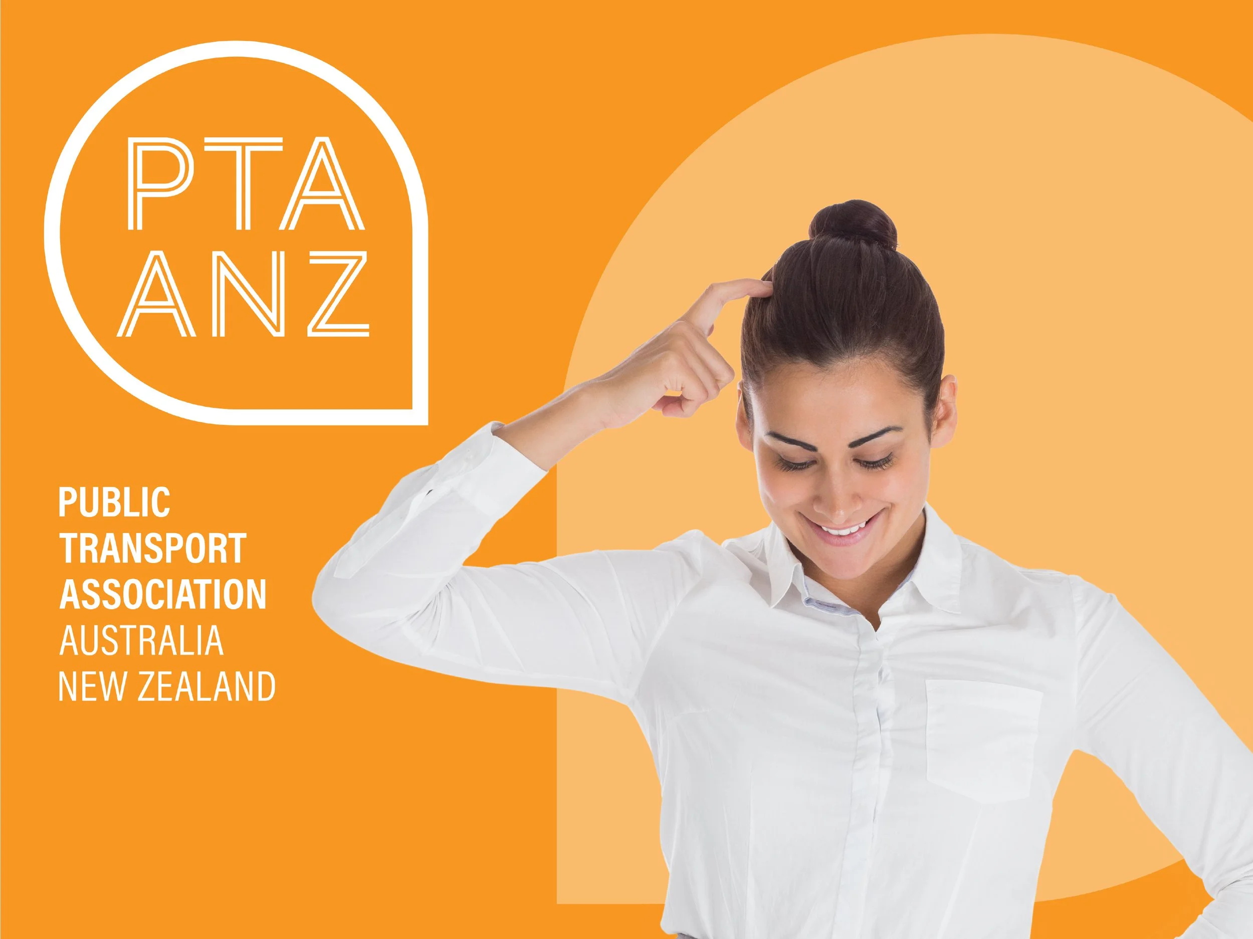 A woman with dark hair in a bun, wearing a white shirt, smiling and touching her head with her right hand, in front of an orange background designed for Zoom meetings. The text reads, Public Transport Association, Australia, New Zealand.'