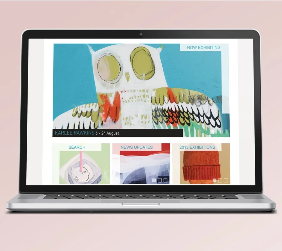 Laptop displaying an art exhibition on Flinders Lane Gallery website with a colourful owl painting, search, news updates, and exhibition sections.