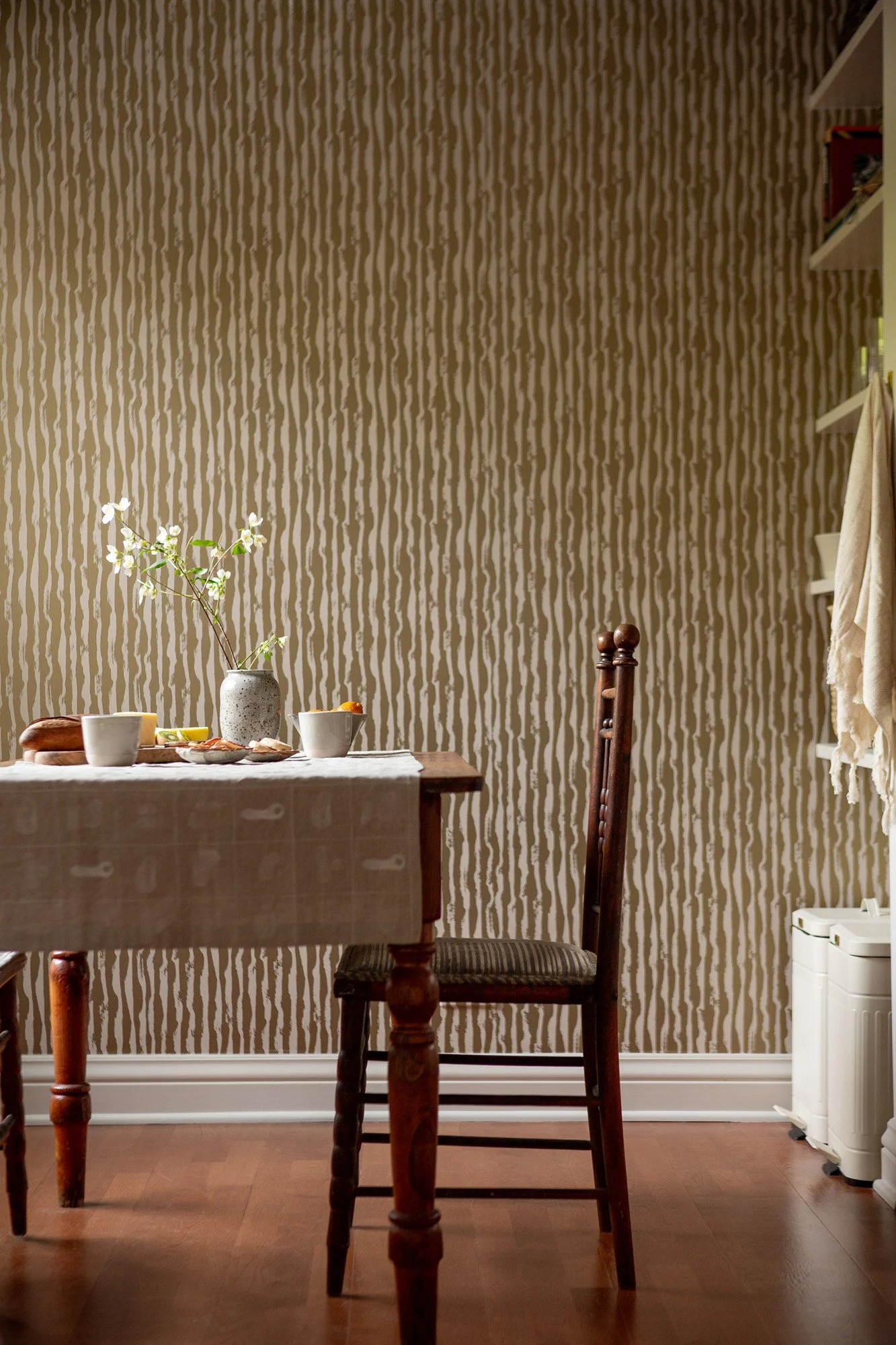 Dining corner at Pine Street Retreat with a vintage chair, embroidered linen tablecloth, and opulent Erica Tanov wallpaper in the furnished Pine Street Retreat in Nob Hill, San Francisco.