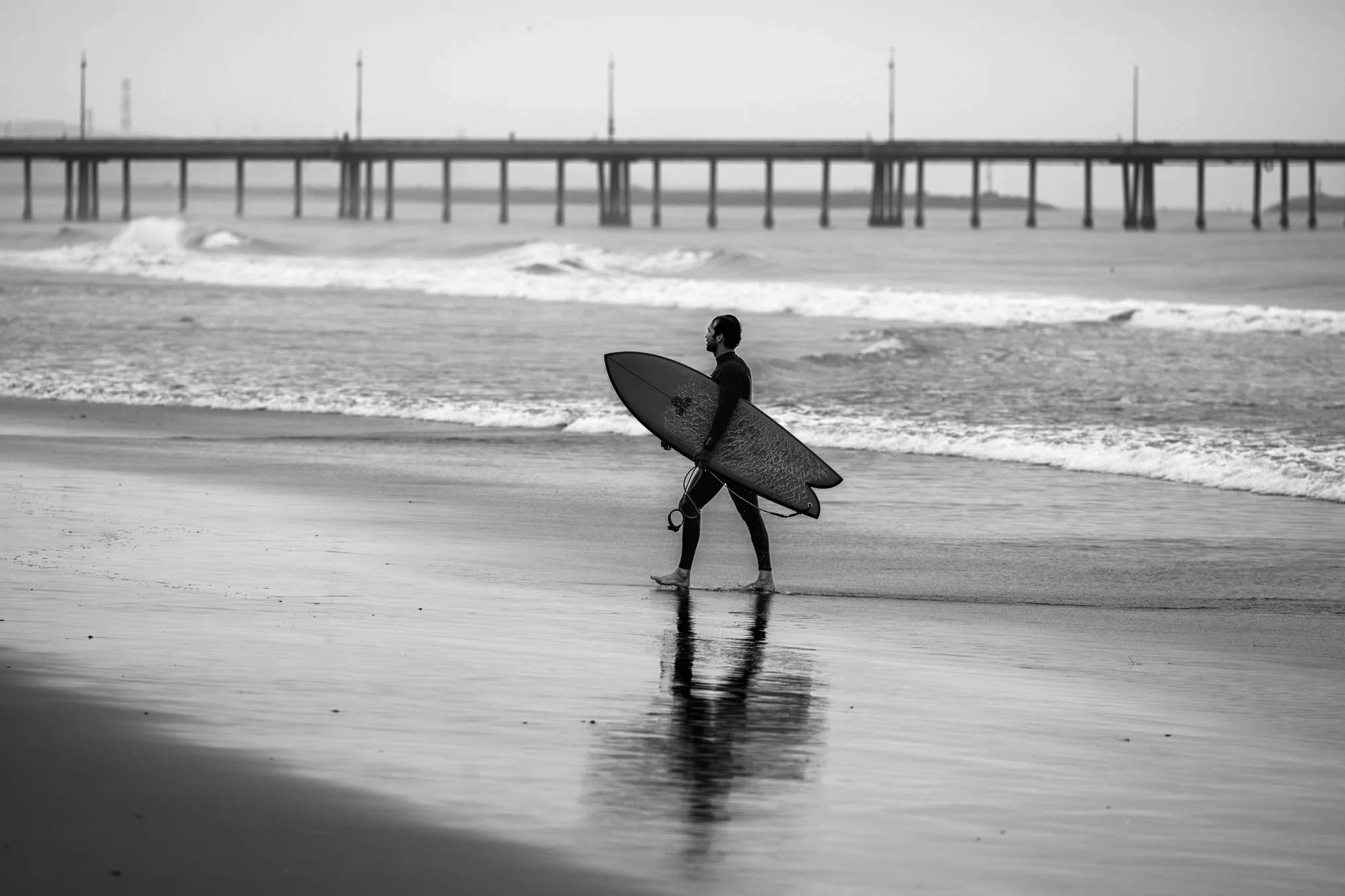 black + white surfer on beach leaving ocean