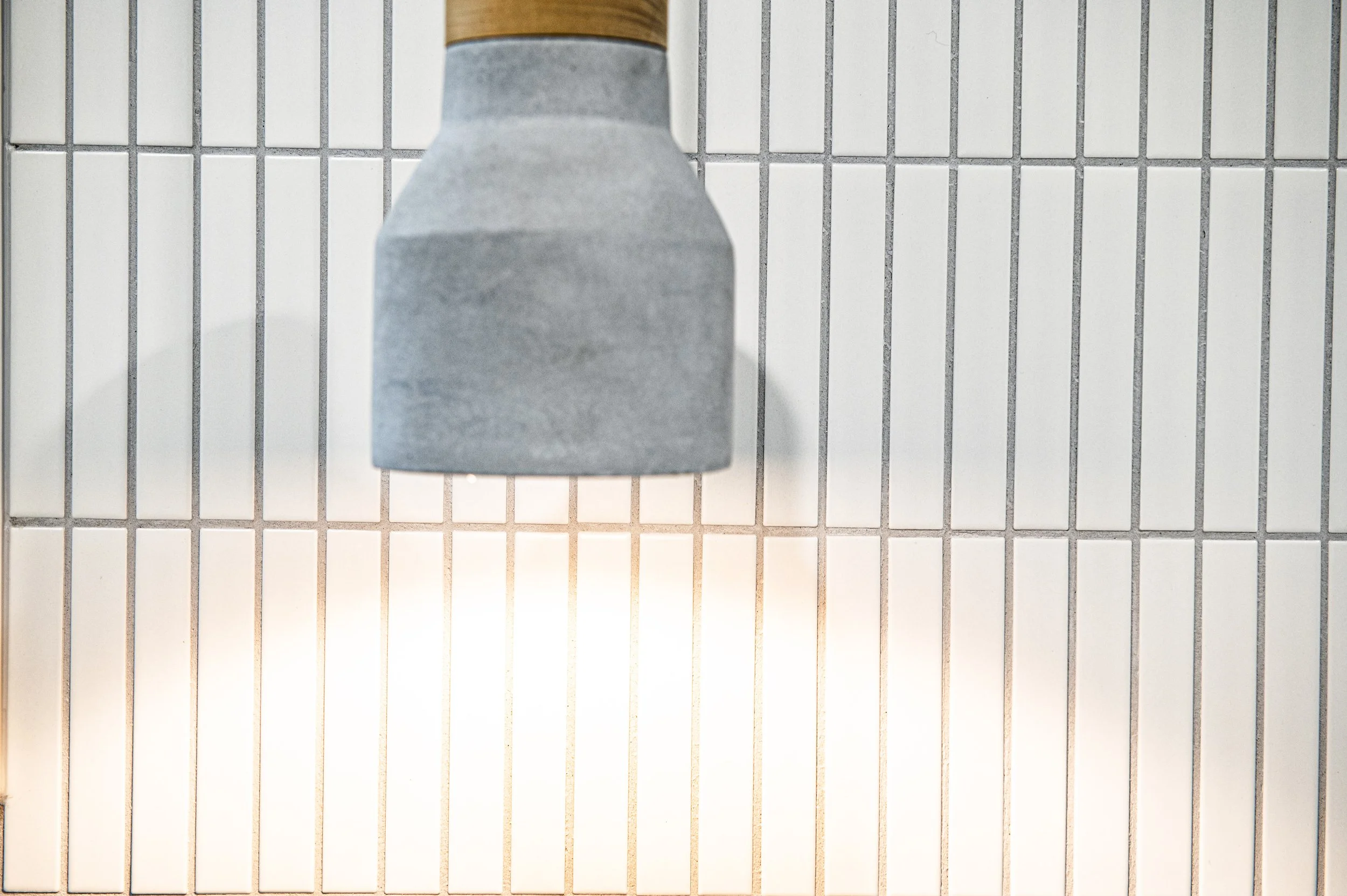 Close-up of a down-facing shower head against a tiled bathroom wall.