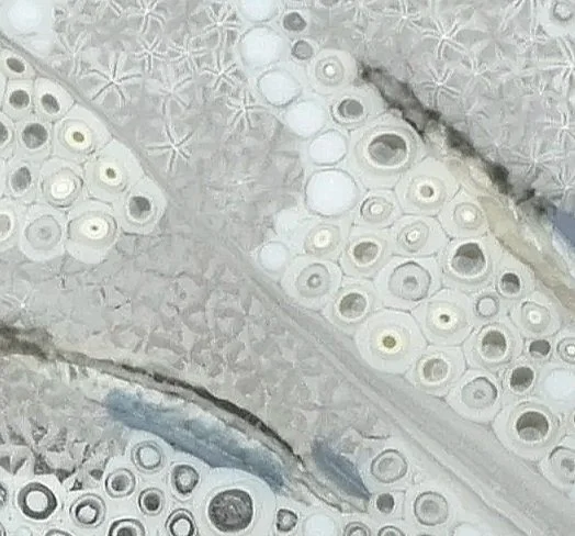 Close-up of a geological formation showing layers of volcanic rock with embedded circular agate stones.