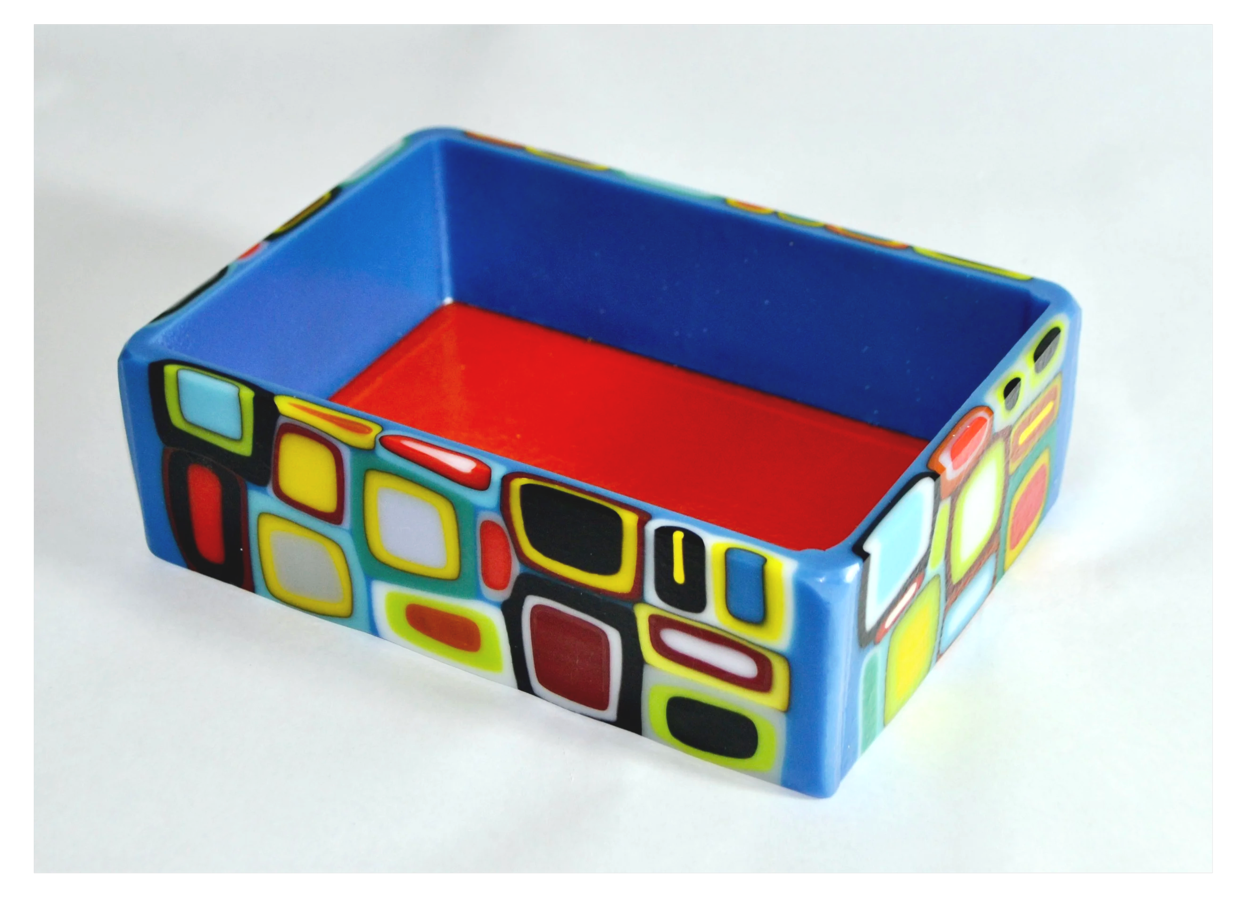 Colorful rectangular container with geometric patterns on the sides, blue interior, and red bottom.