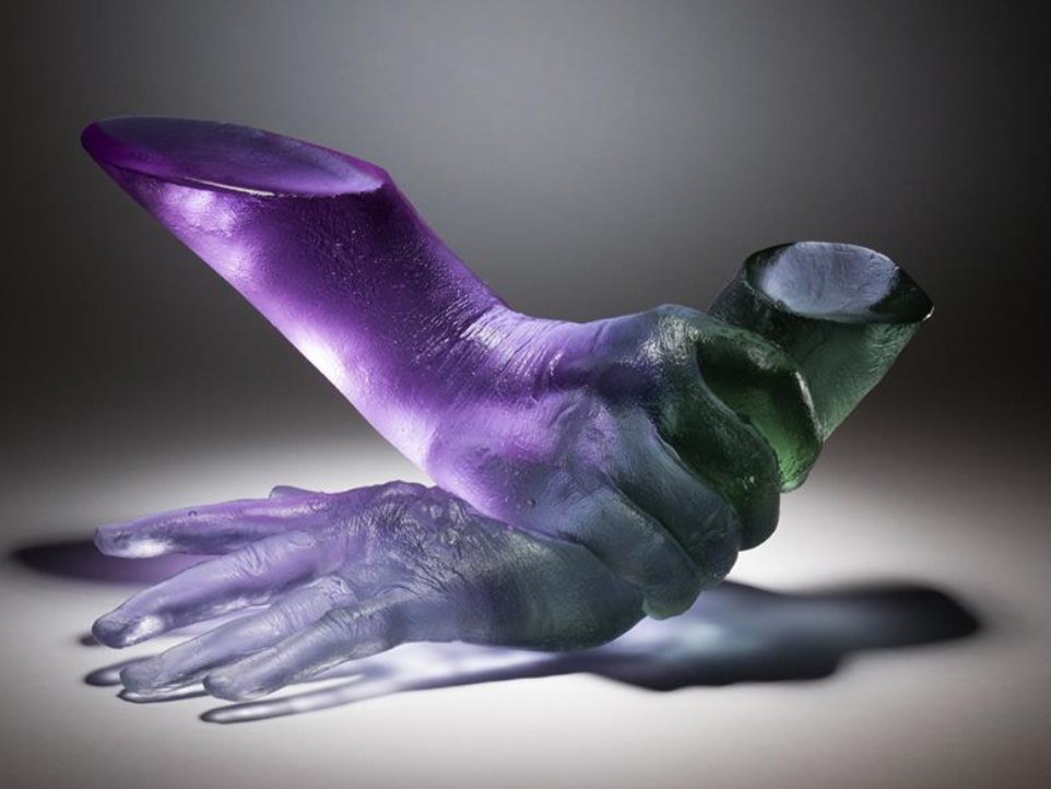 A sculpture of two hands, one reaching out and the other forming a cup shape, painted with purple and green hues.