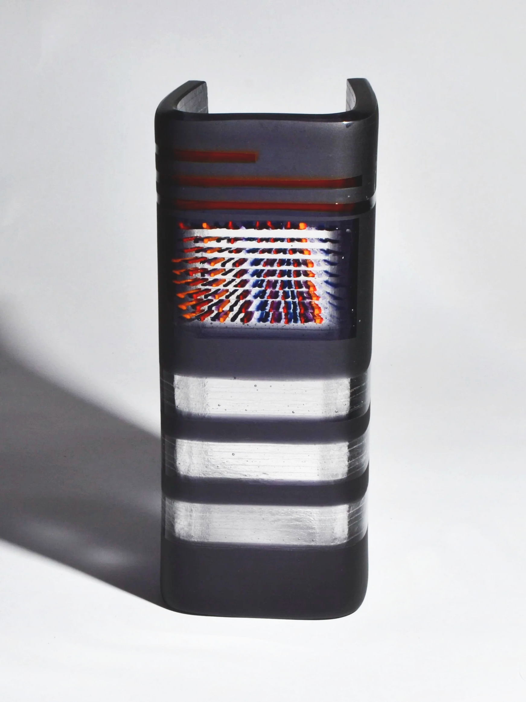 An artistic photograph of a lighter with a fiery flame, casting a shadow on a white surface.