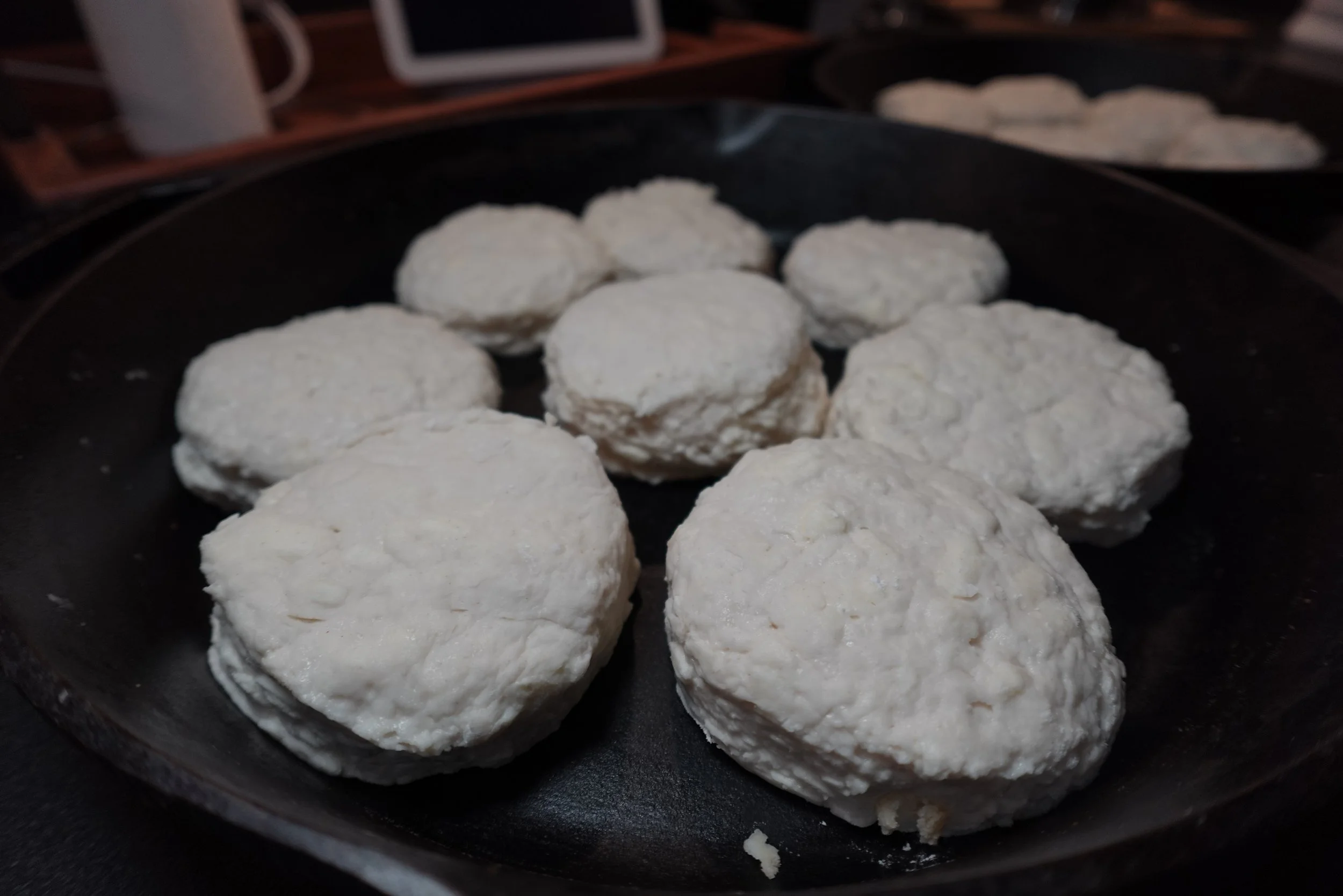 Raw biscuit dough balls on a black baking sheet