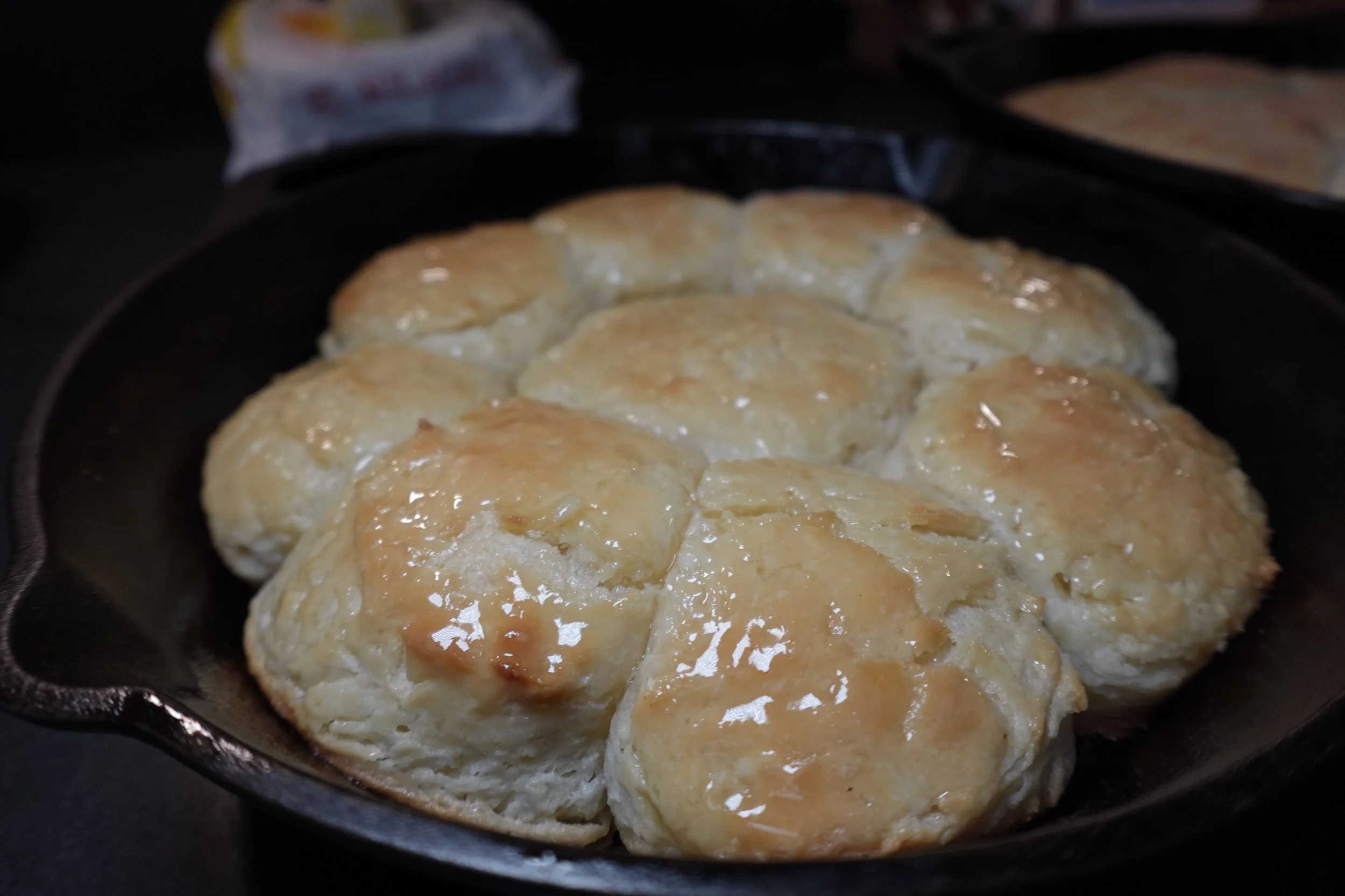 Baked biscuits in a cast iron skillet, with golden brown tops and melted butter glaze.