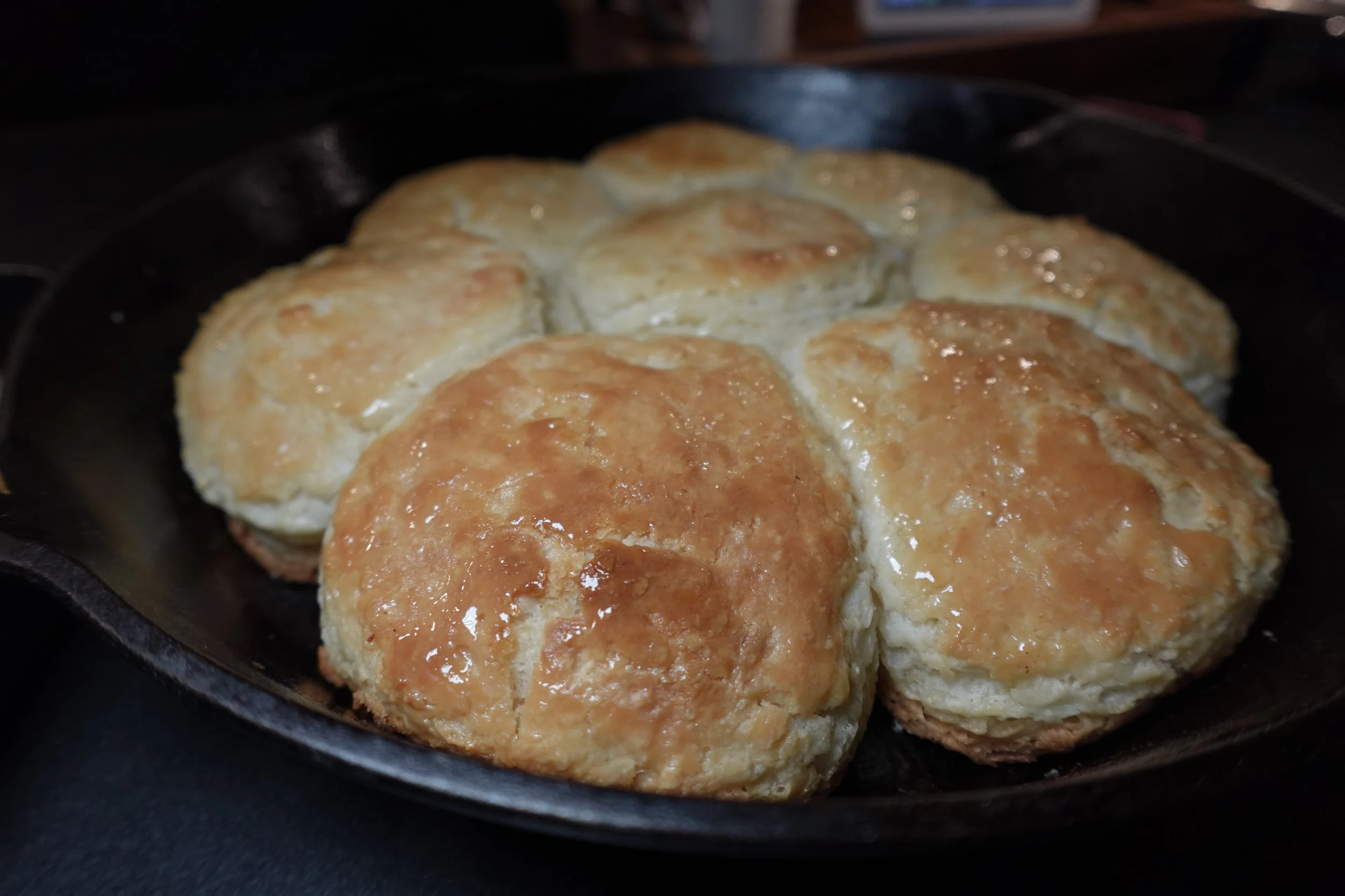 Biscuits with golden-brown tops baking in a cast iron skillet.