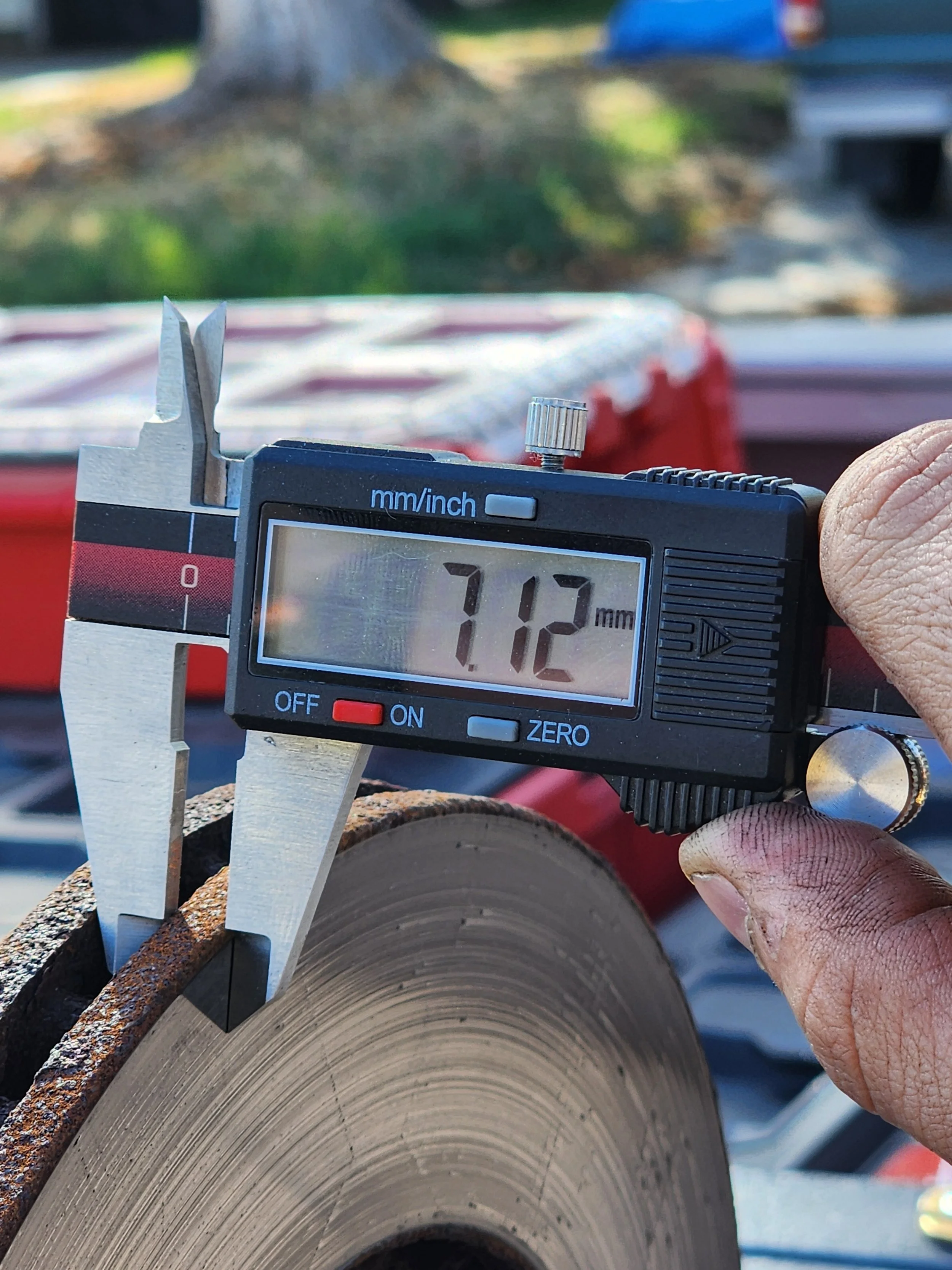 A digital caliper measuring the diameter of a brake rotor, showing 71.2 millimeters.