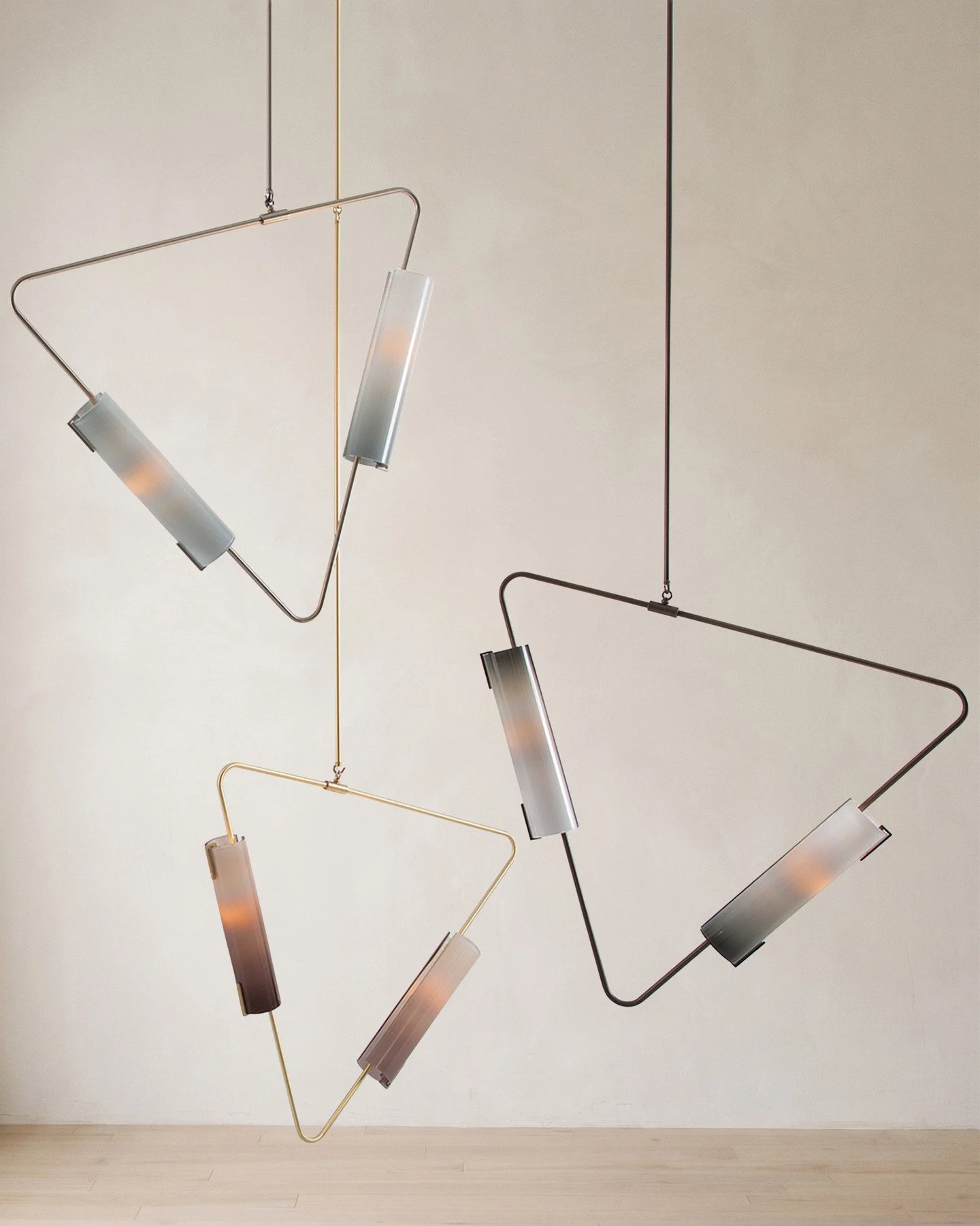 MUSE PENDANT.⁠
⁠
The Muse Pendant takes the movement of Avram Rusu Studio&rsquo;s Continuum series and pulls it into a quieter, more contained geometry. A triangular brass line holds two cylindrical shades at opposing angles, so the fixture reads lik