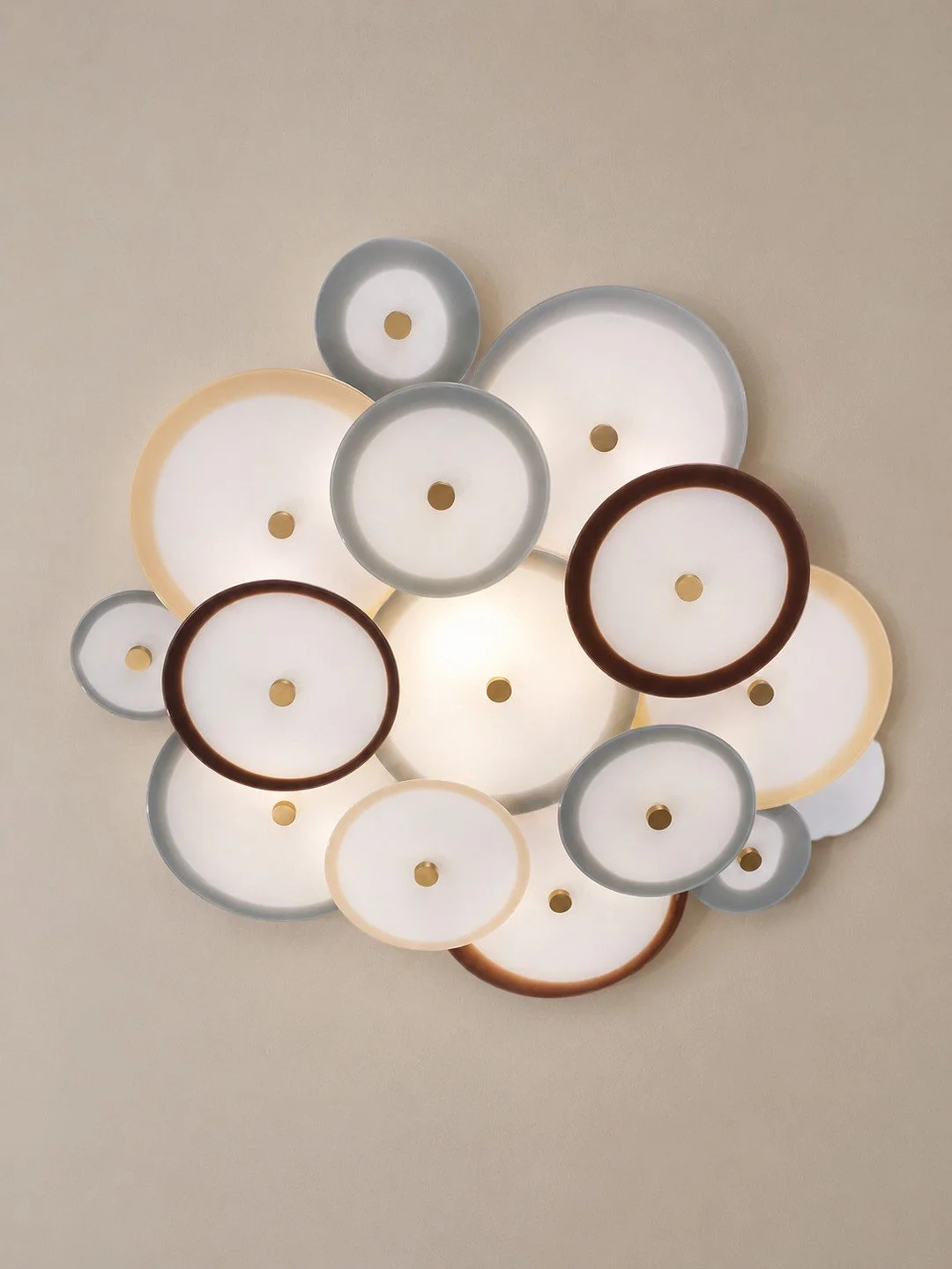 NYMPHAEA CHANDELIER. A layered composition of handblown glass discs, the Nymphaea Chandelier from @avram_rusu_studio draws from floating lily pads and clustered blooms. Overlapping translucent tones give the fixture its depth, while delicate brass ha
