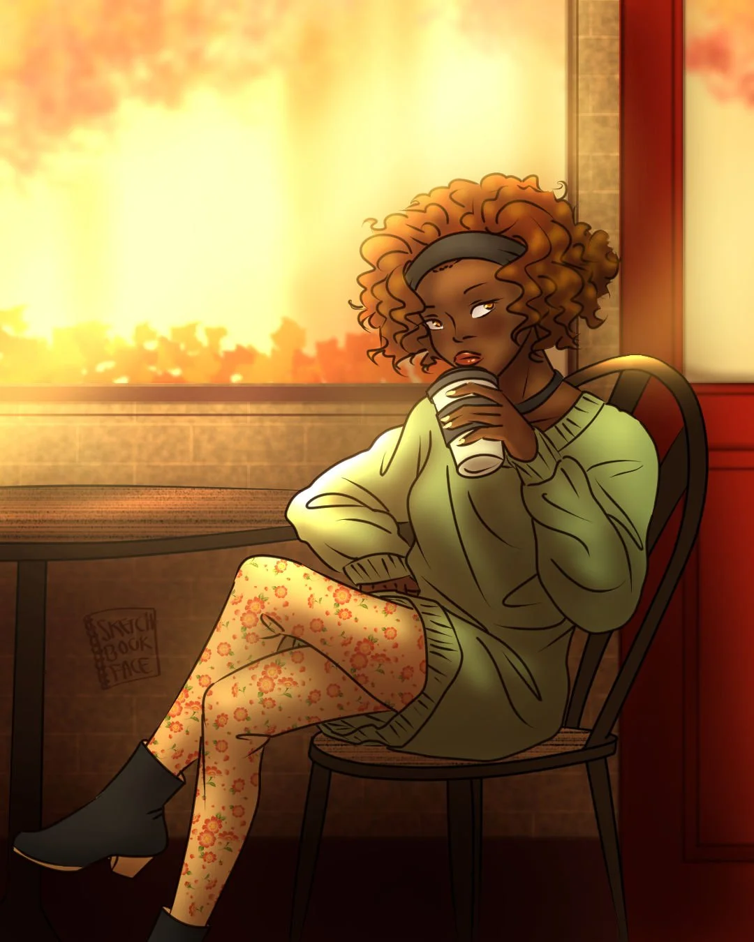 A girl with curly short hair sits in a cafe holding a pumpikin spice drink. She wears a green sweater tunic, floral leggings, and low-heeled boots.