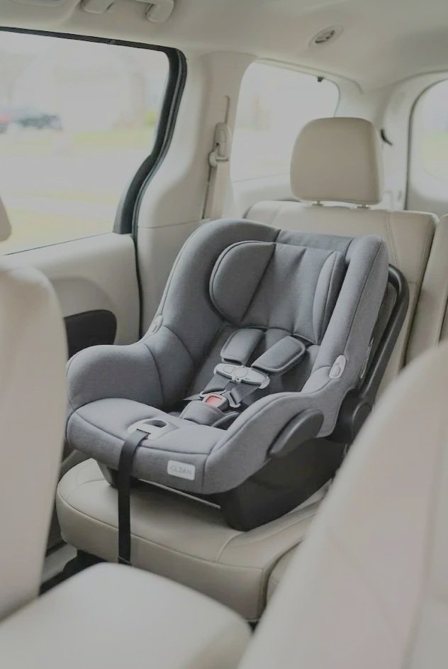 Child car seat installed in the back seat of a vehicle with beige interior.