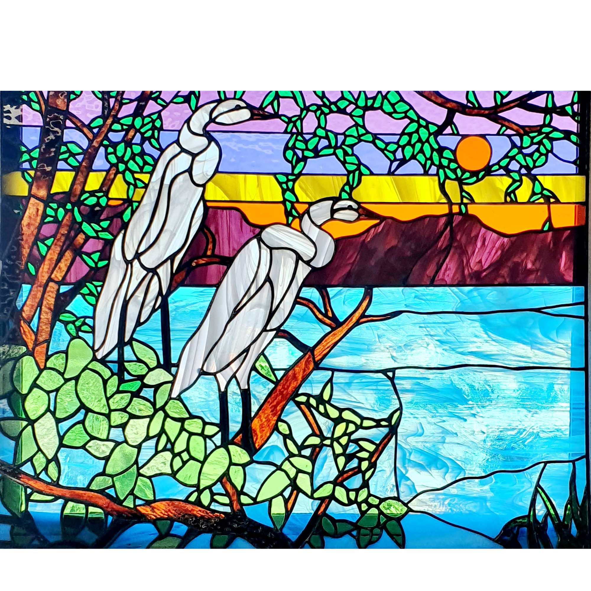 Stained glass art depicting two herons by a body of water, with a tree, orange sun, and purple sky in the background.