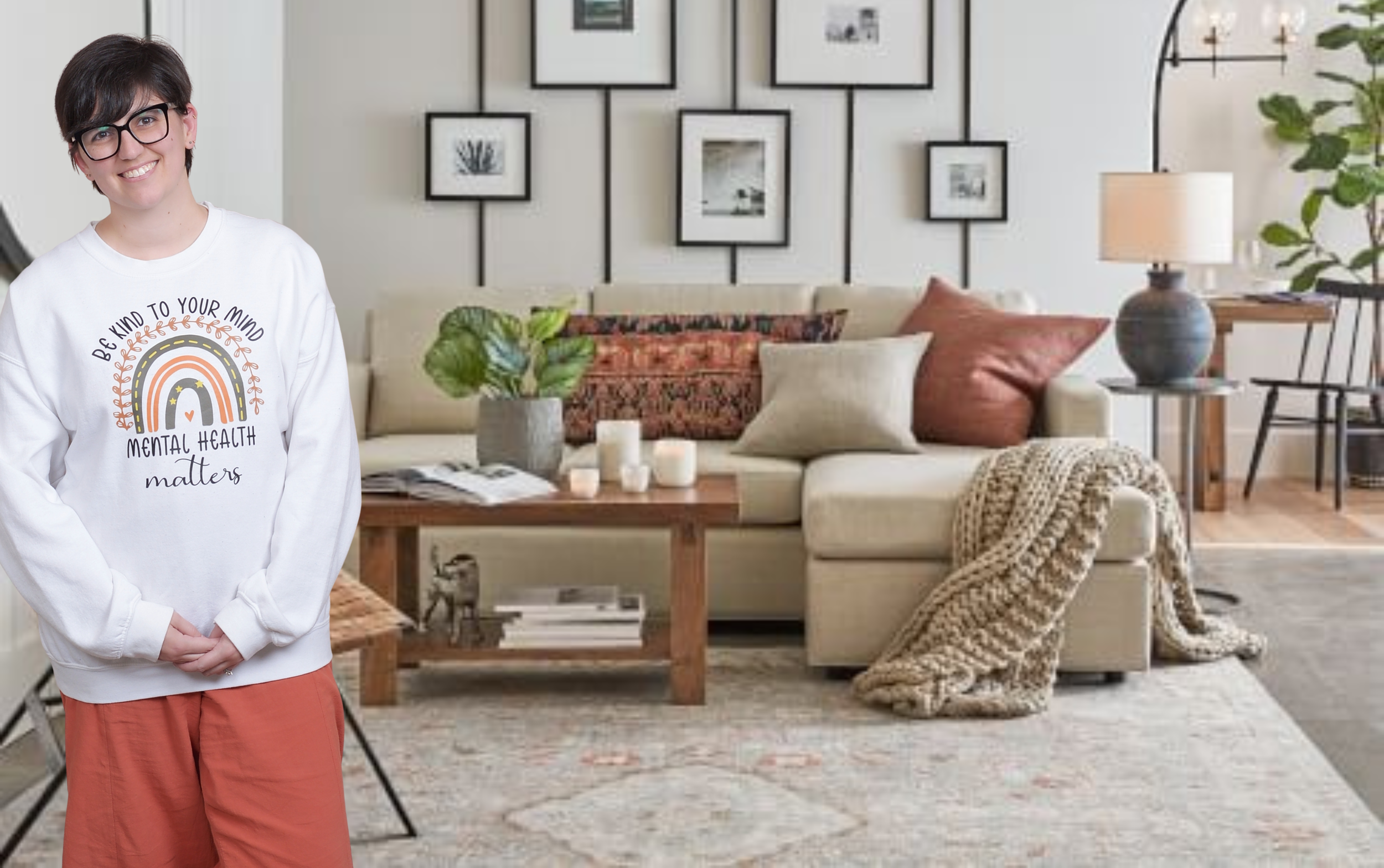 Kirsten Dantin LPC Headshot. White sweatshirt that reads 'Be kind to your mind, mental health matters,' standing in front of a cozy, modern living room with a beige sofa, colorful pillows, a wooden coffee table, candles, and wall art.