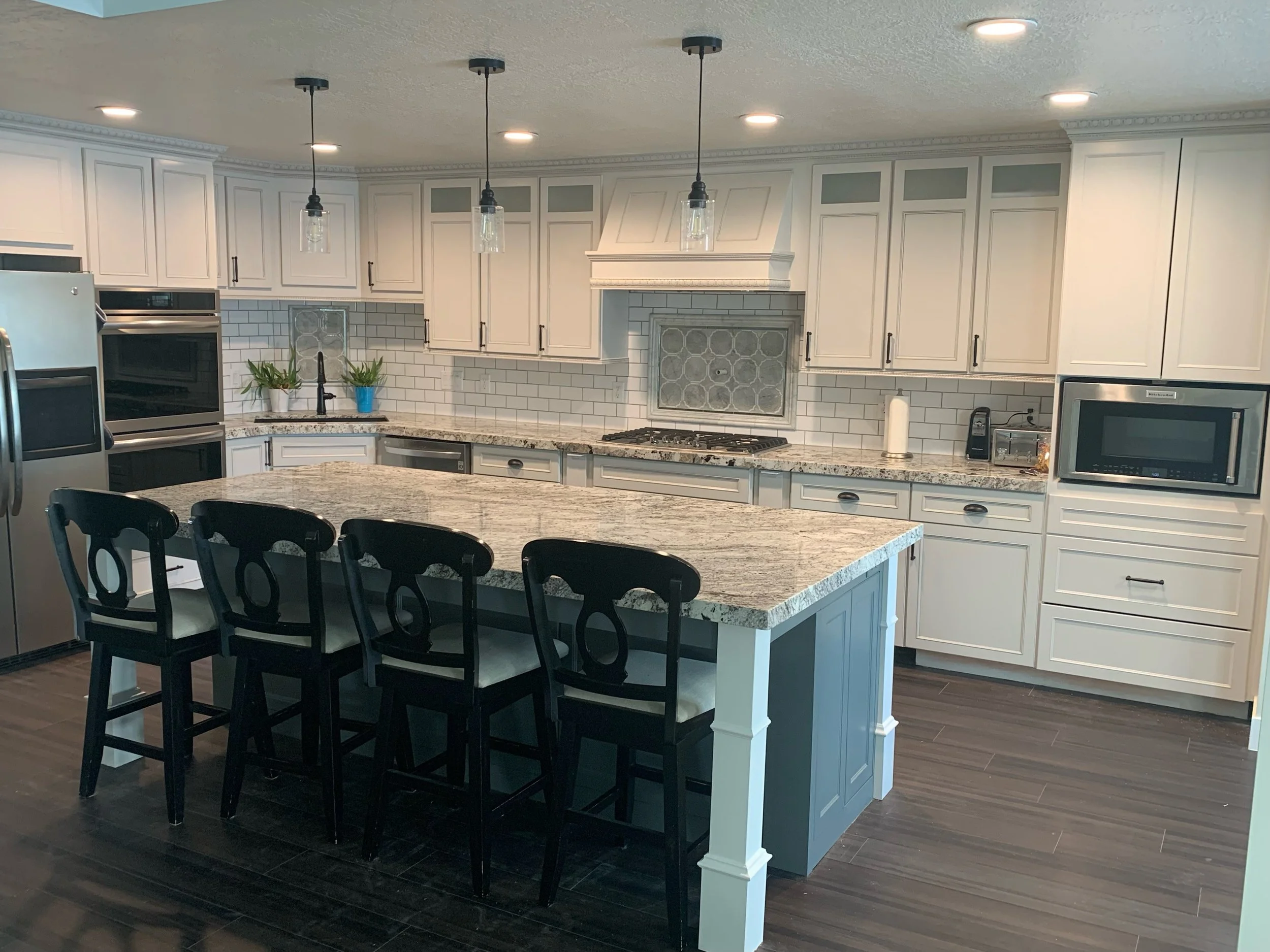 Fully refinished cabinets and custom backsplash after a full house fire. Features a  dual-tone kitchen, with gray and white island, built with custom posts and what's not shown is a built in cubby for folding tables along the length of the island. Up