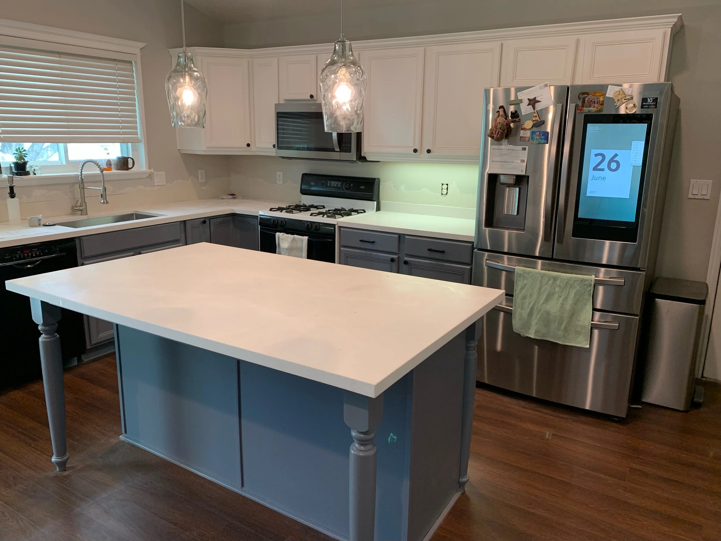This customer also requested a dual-toned kitchen with a clean white base on top, and cool-toned gray island and bottom cabinets. This particular job also required replacing the counter-top which we hand styled, sized, and polished, installed over a 