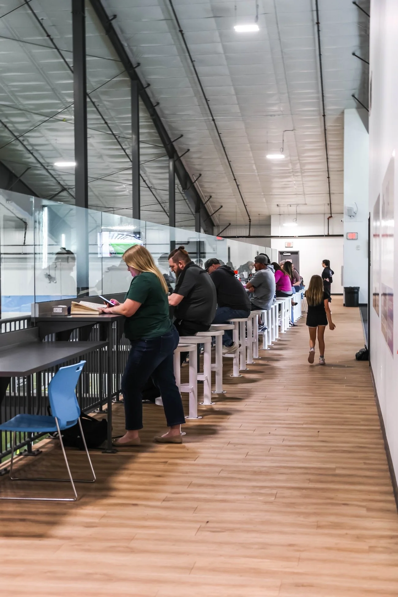 People sitting at a bar with a window view of an ice rink, watching ice hockey.
