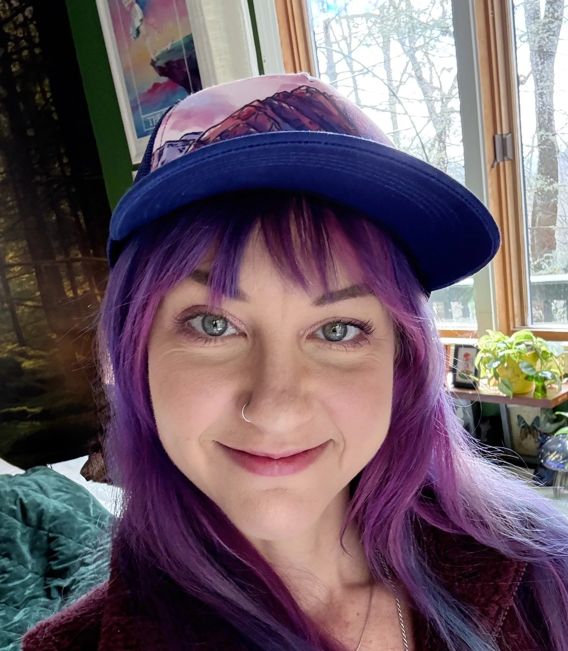 woman with purple hair and a cap smiling