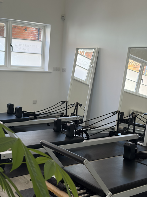Pilates reformer machines in a bright exercise studio in Grayshott surrey with a mirror and window.