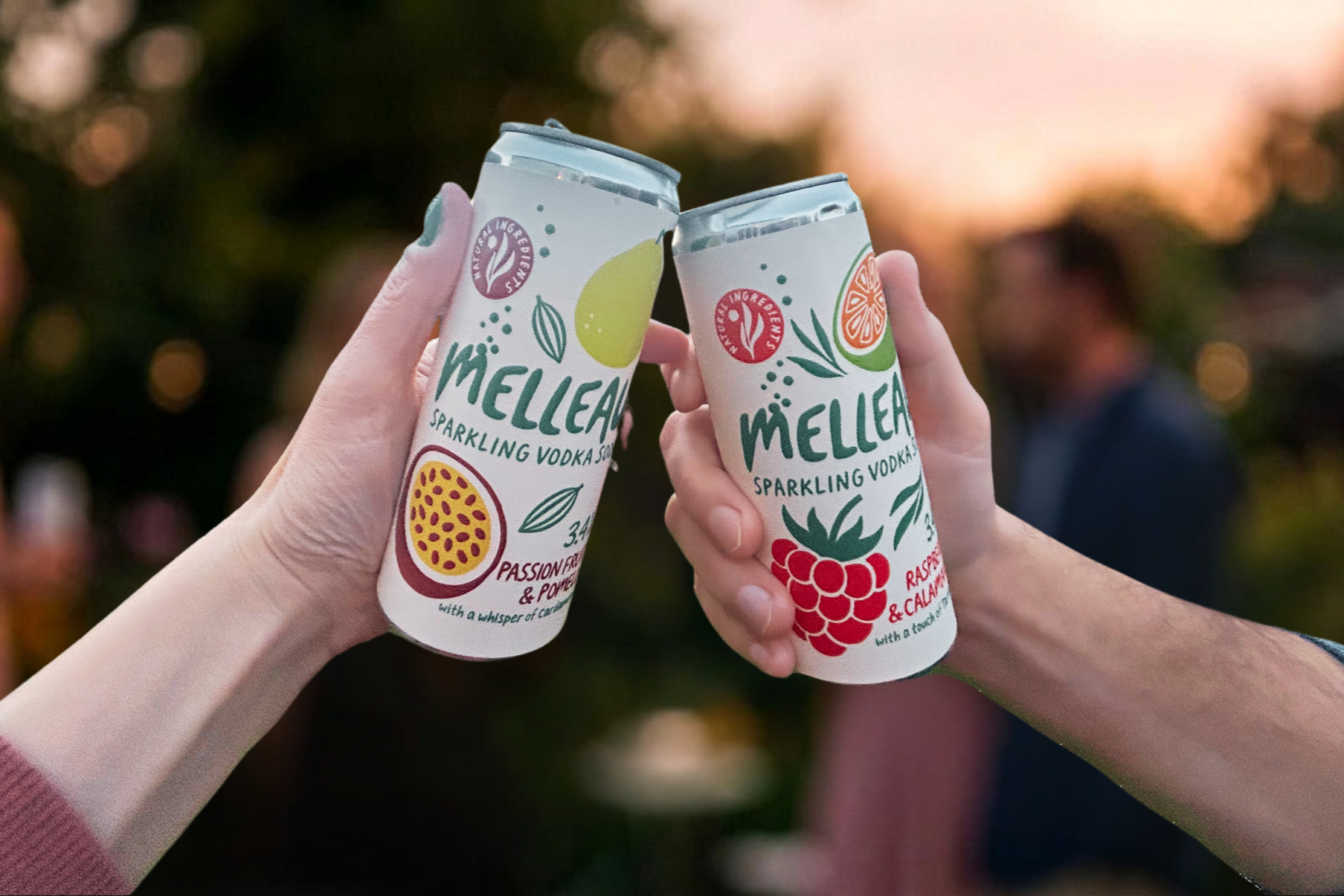 Two people toasting with cans of Mellaer sparkling vodka soda, one with passion fruit and pomegranate flavor and the other with raspberry and calamine flavor, outdoors at sunset.