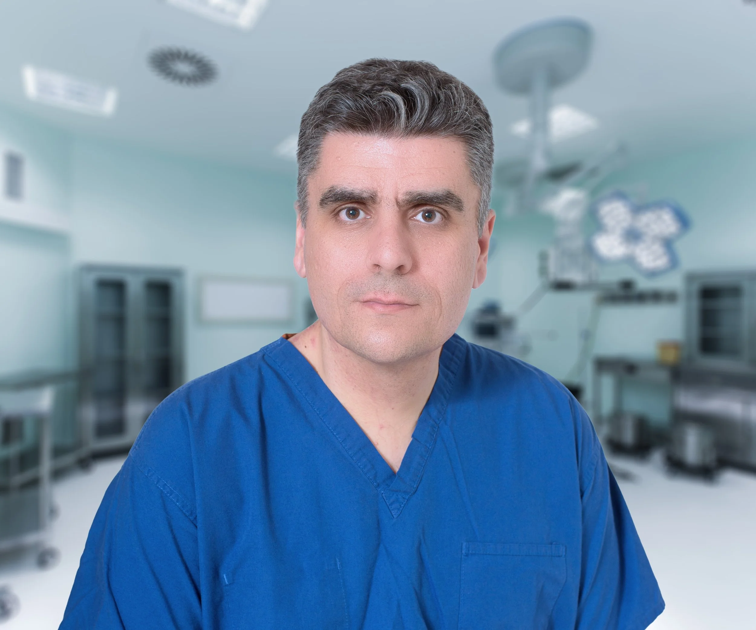 A male healthcare professional in blue scrubs standing in a modern hospital operating room