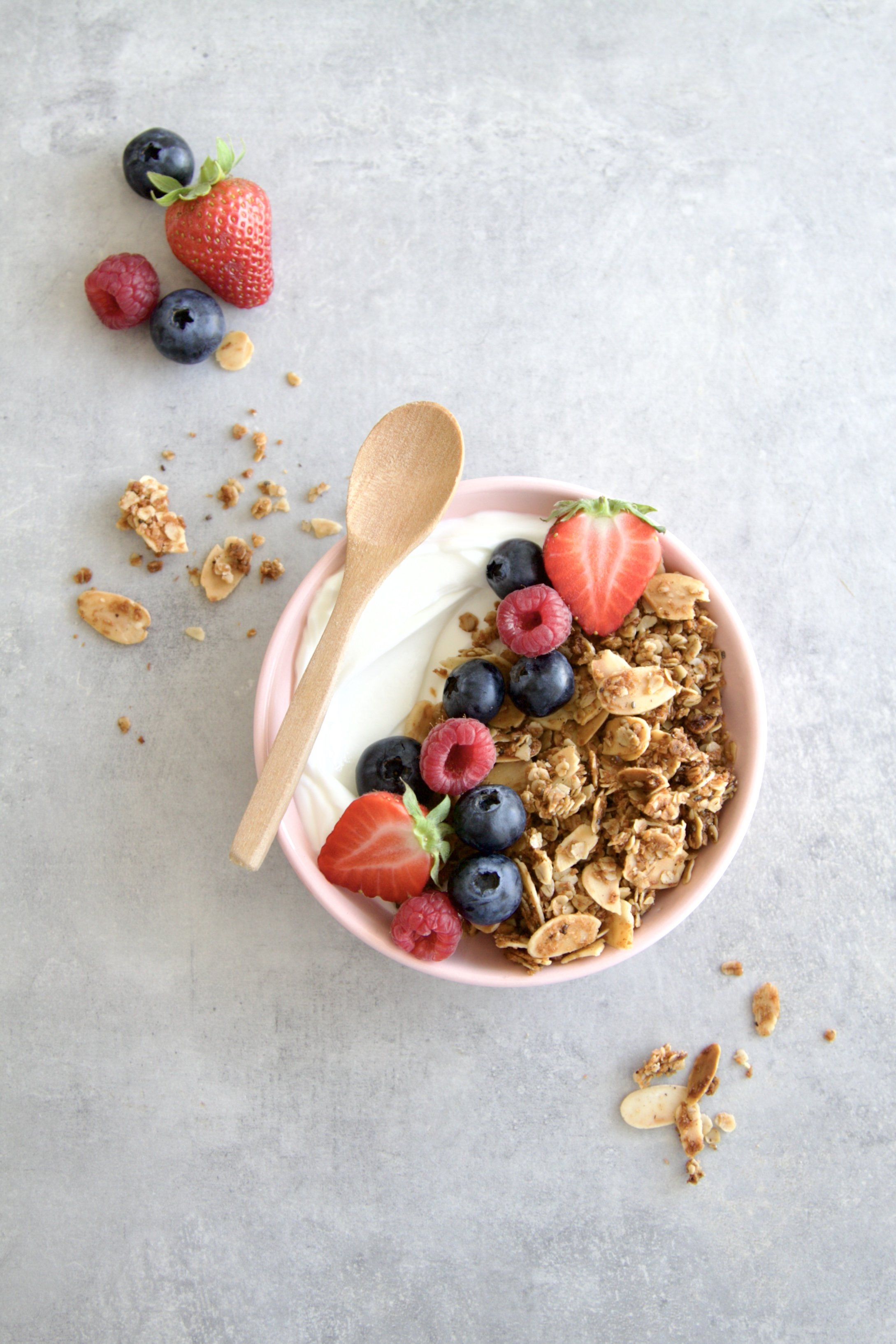 bowl of skyr Jogurt topped with coconut almond chia granola and fresh berries with a wooden spoon on the rim
