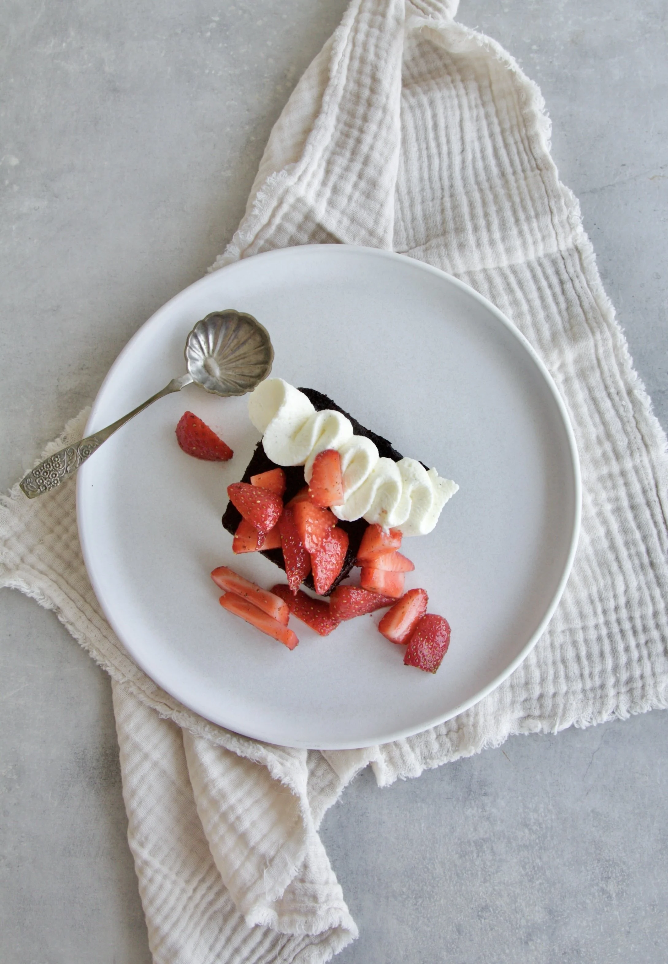 slice of super moist chocolate cake topped with mascarpone vanilla cream and strawberries