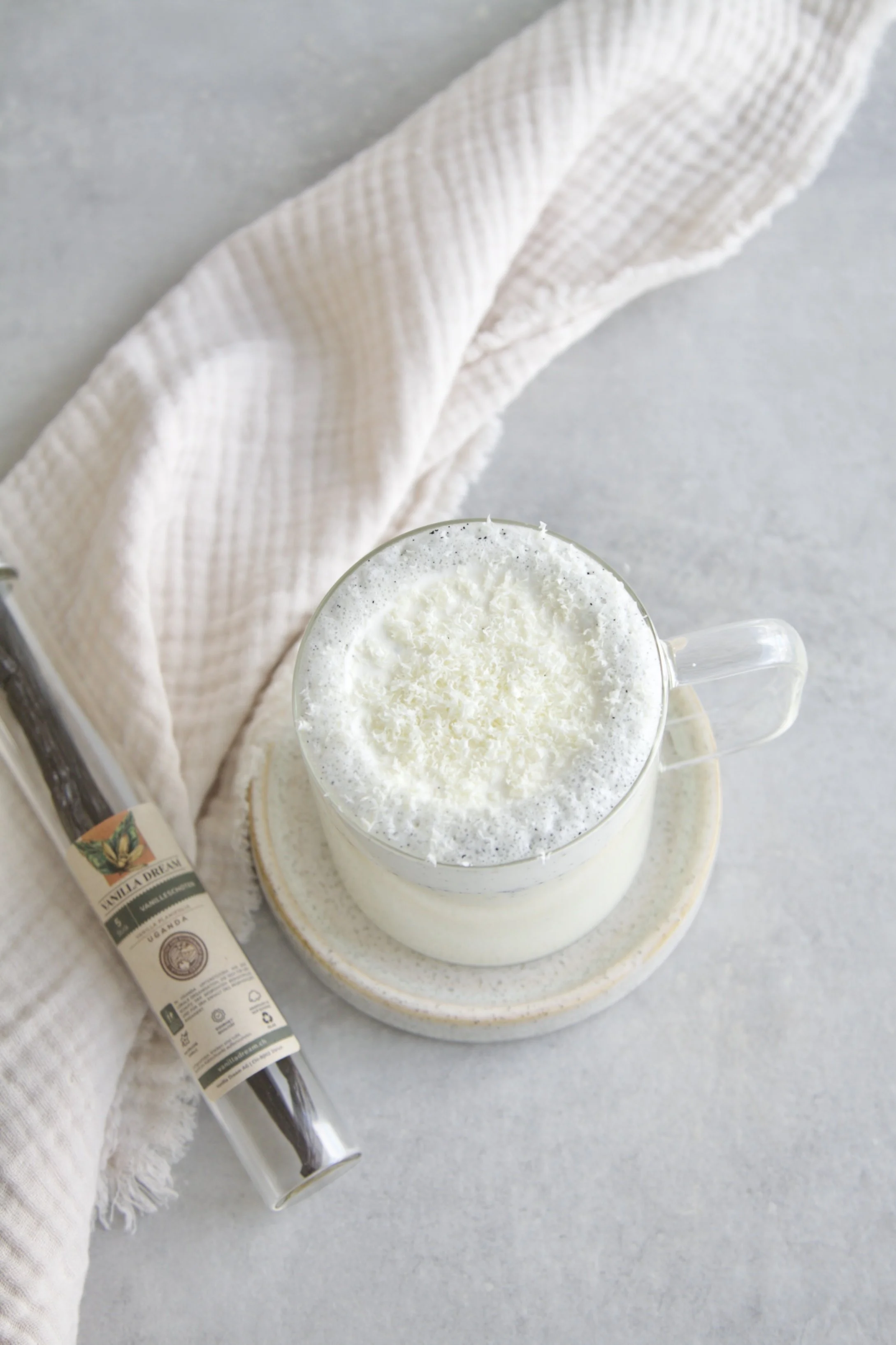 Top shot of a vanilla hot chocolate with a glass tube of vanilla beans next to it from Vanilla Dream