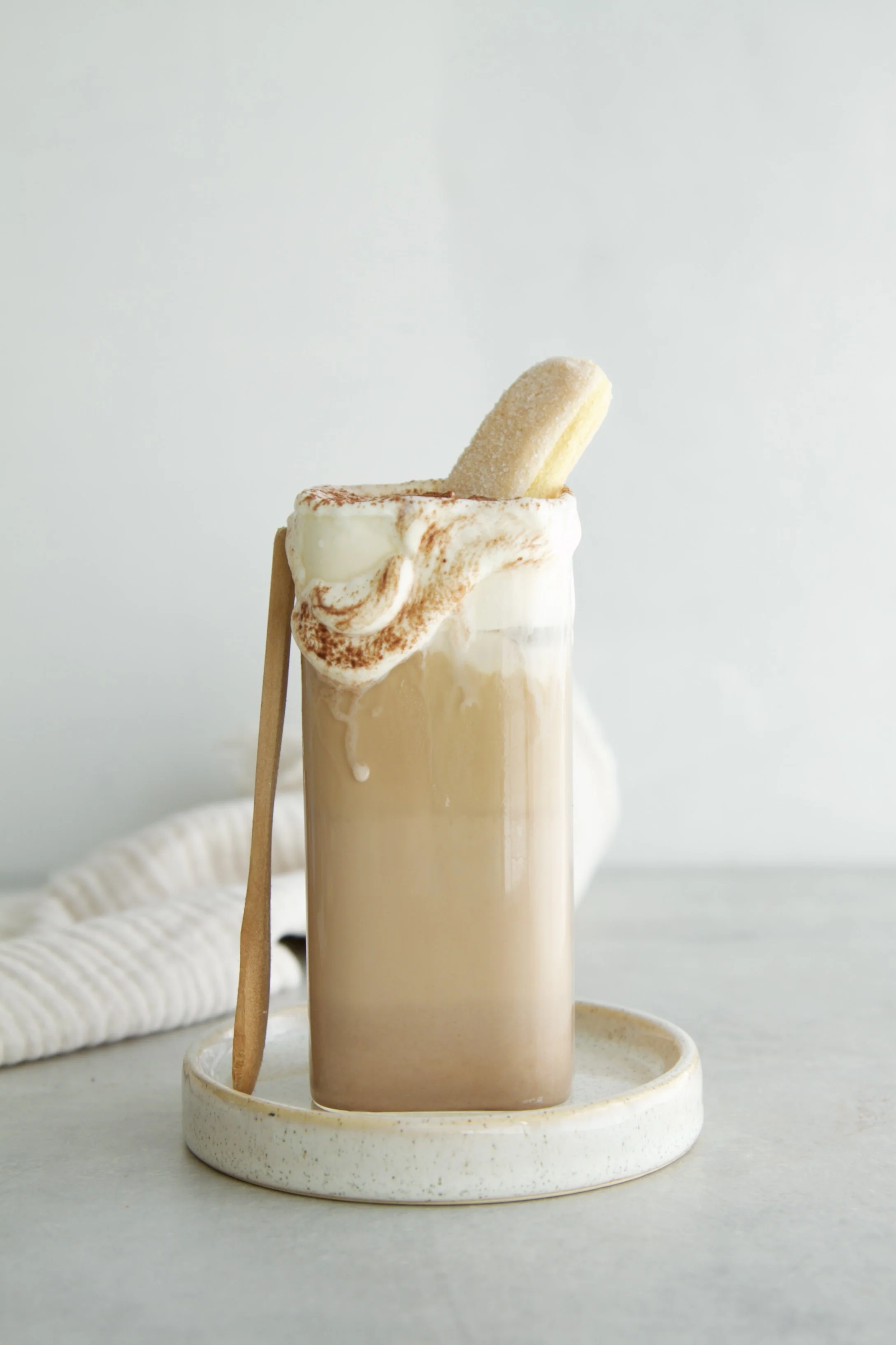 tall glass of tiramisu latte with cold foam dripping down the rim