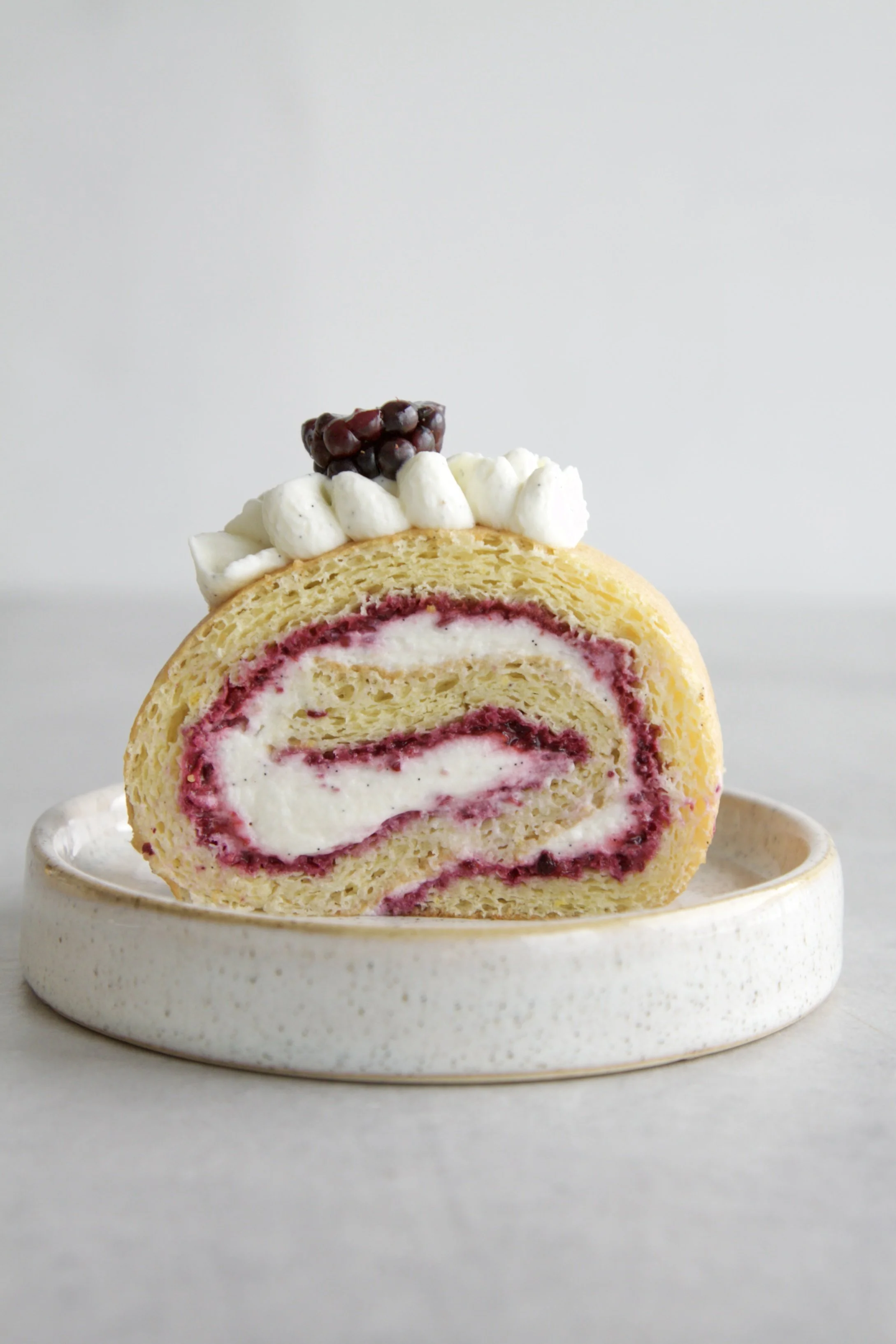 cut of a blackberry vanilla Swiss roll cake