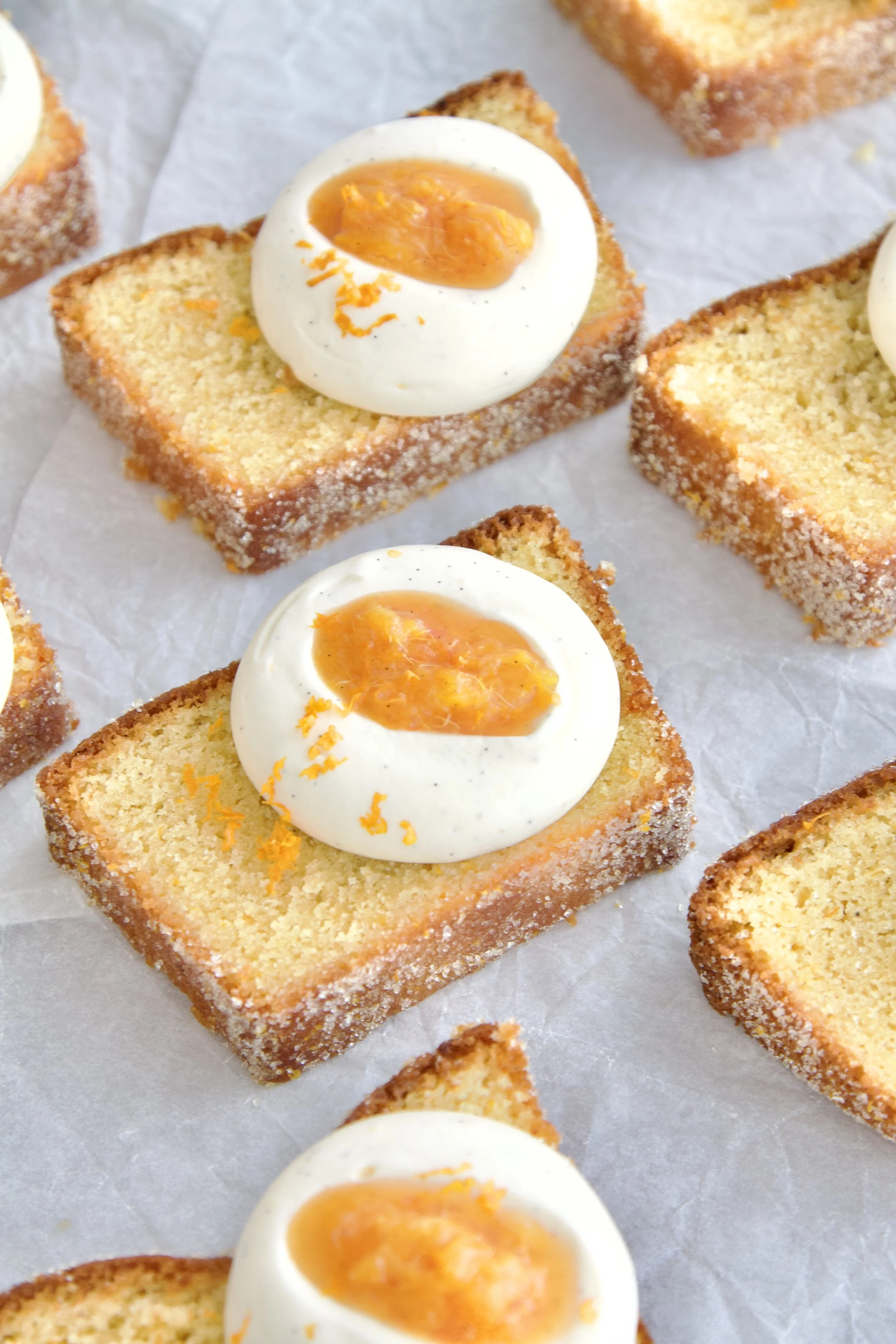 many slices of orange vanilla cake with the top view, each slice with vanilla cream and orange compote on top