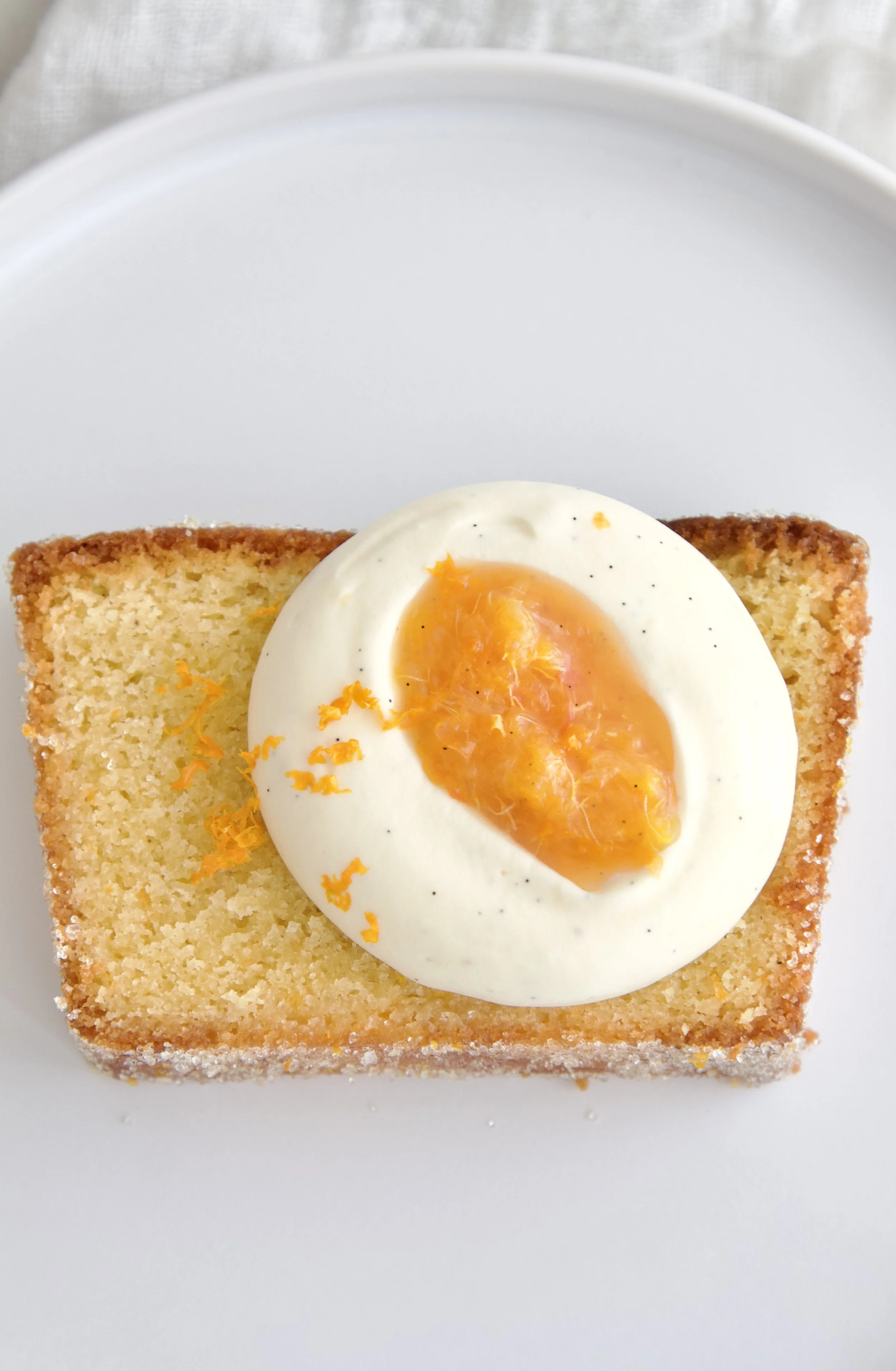 slice of orange vanilla cake with vanilla cream and orange compote on top with a sugared crust