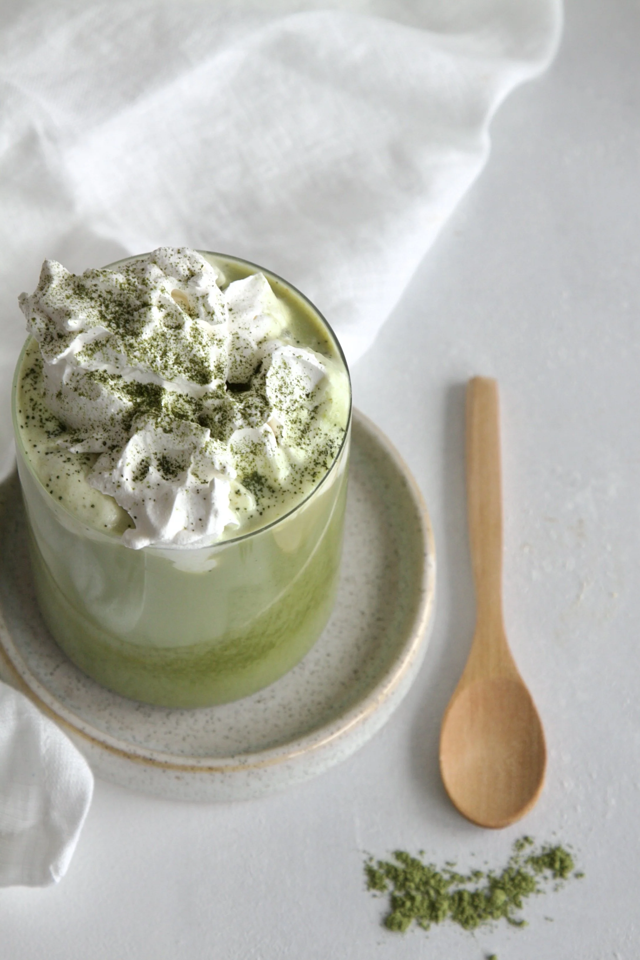 Top shot of a pistachio matcha latte topped with whipped crem and matcha dusting