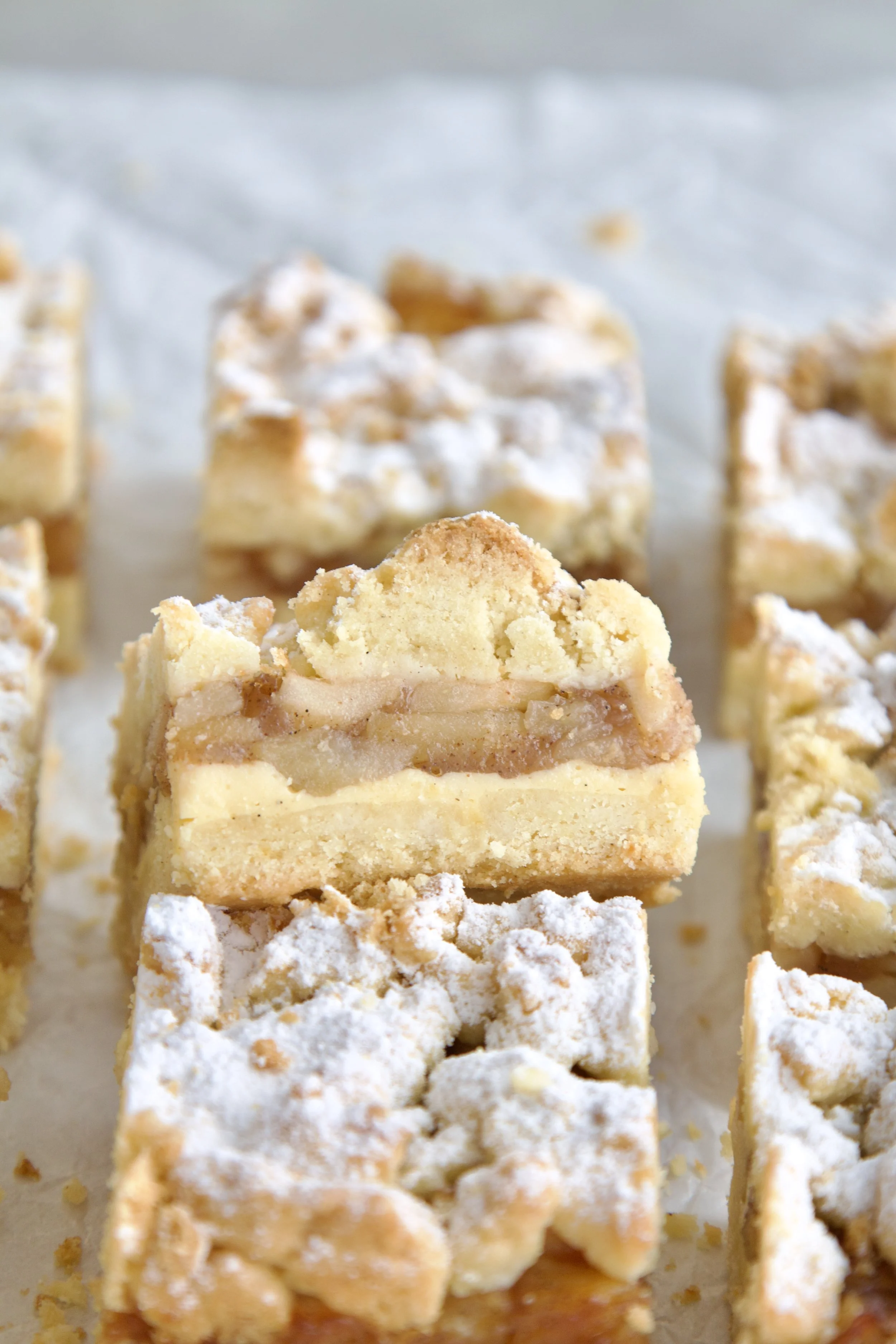 apple crumble cake slice where you can see the layers of crumble, apple cinnamon filling and vanilla pastry cream