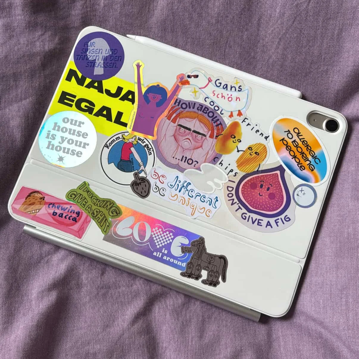 Ein Laptop mit vielen bunten Aufklebern und Stickern auf einem violetten Stoff.