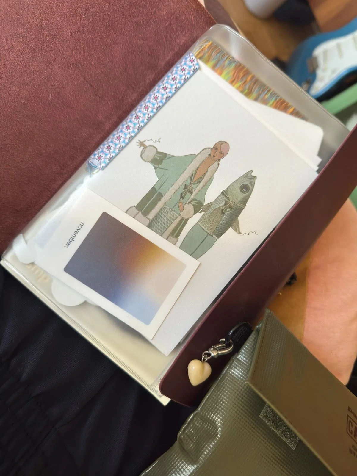 Offene Schachtel mit Comic-Billede einer Frau mit Fisch-Kopf, Regenjacke und Koffer